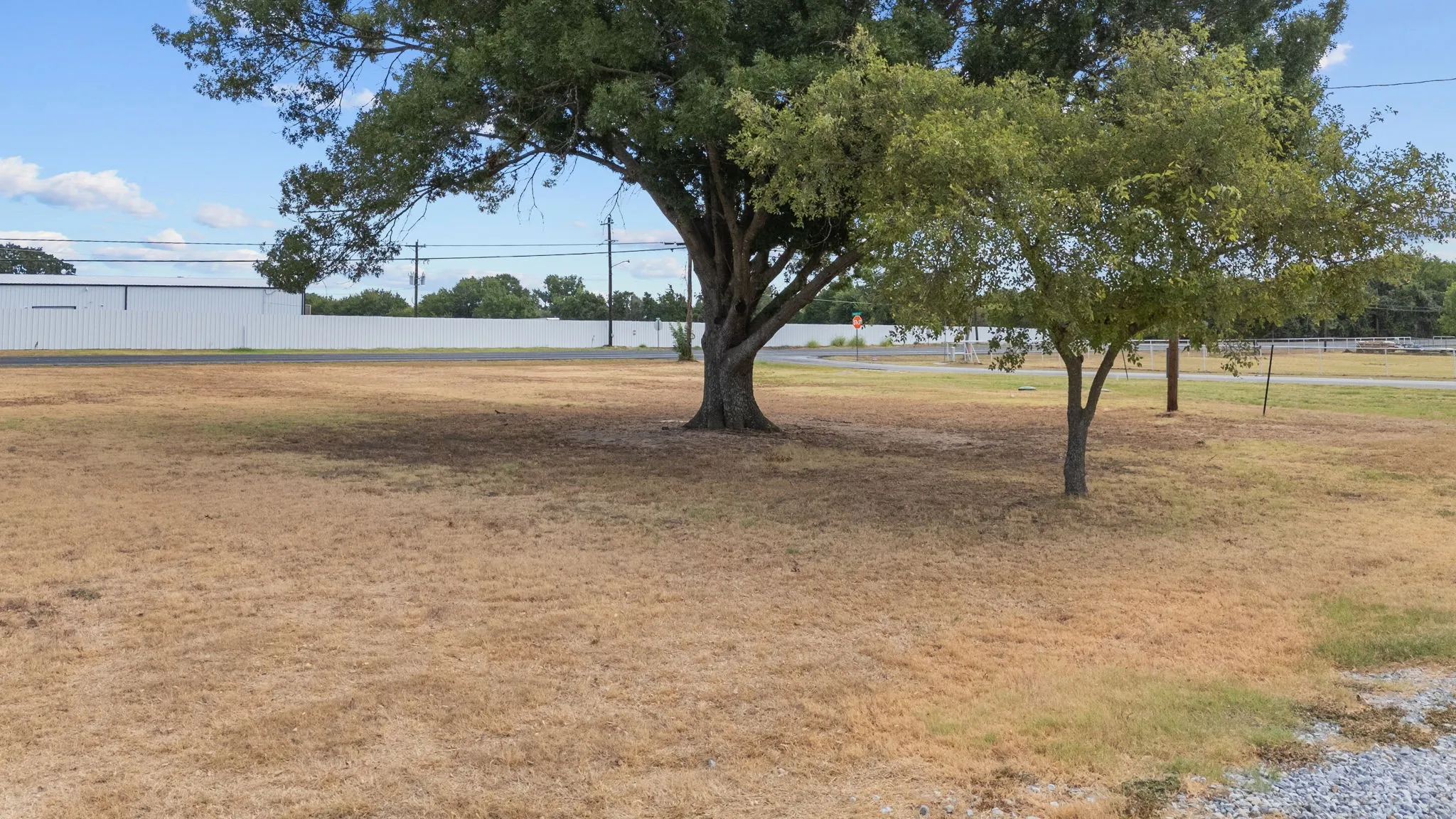 Open yard with mature trees providing additional usable outdoor space around the improvements.