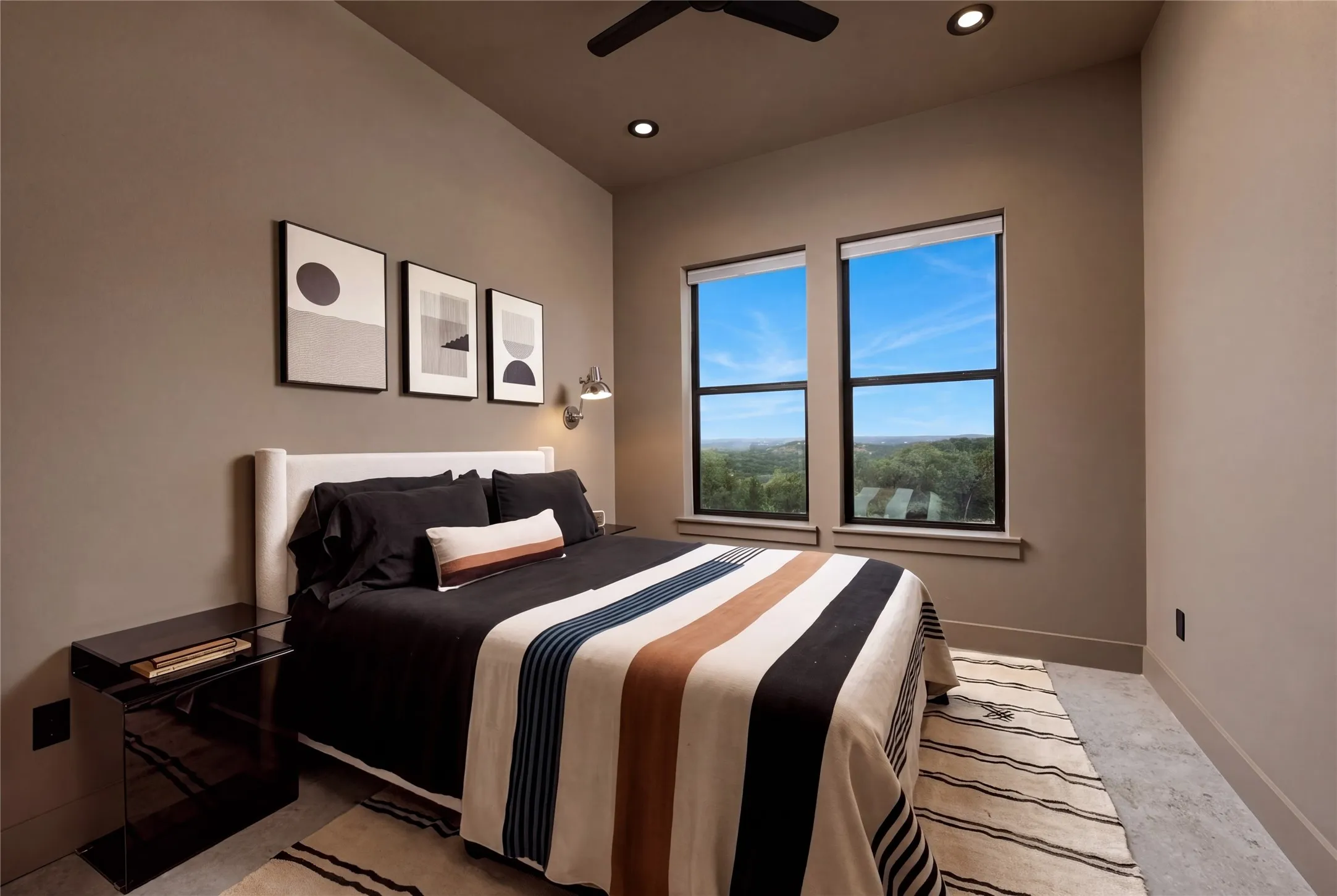 High ceilings and tall windows framing scenic distant views define this inviting bedroom space.