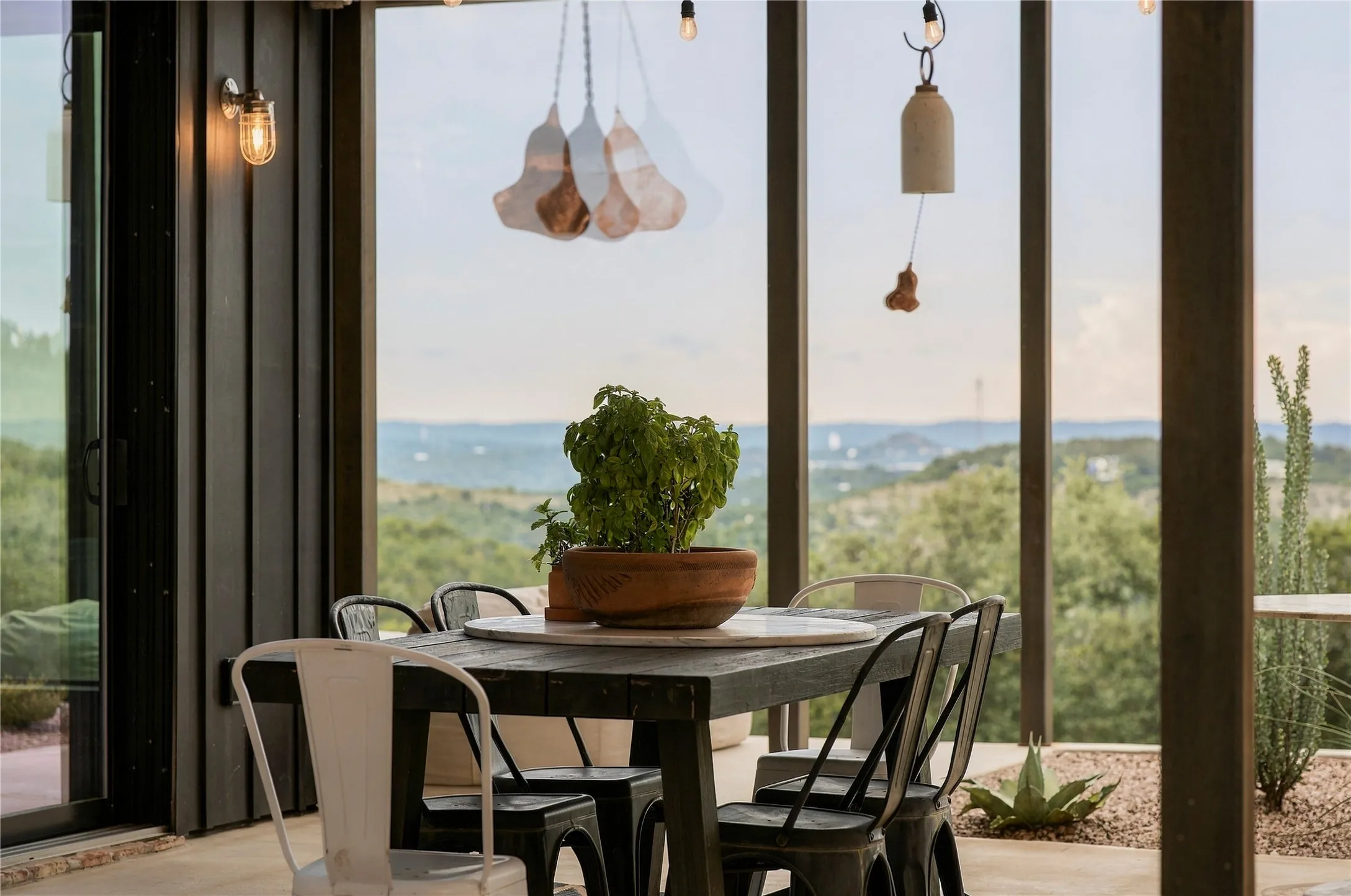 A sheltered outdoor dining area frames distant views of rolling hills and water.