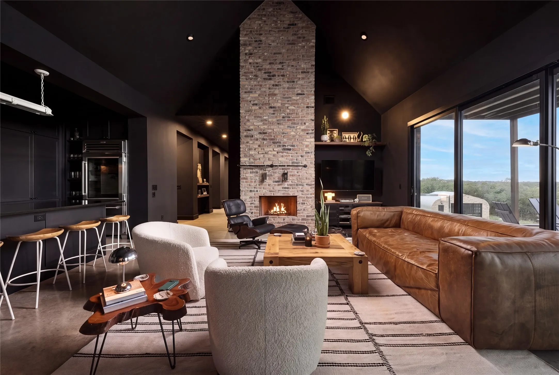 Dramatic dark vaulted ceilings rising above polished concrete flooring frame a Chicago brick floor-to-ceiling fireplace.