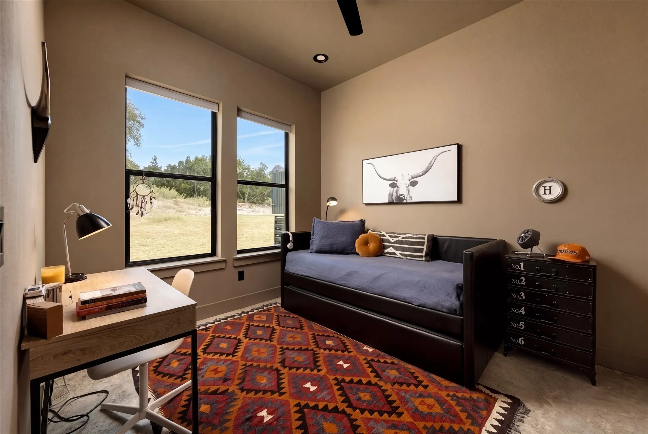 High ceilings and tall windows framing scenic outdoor views define this modern secondary bedroom.