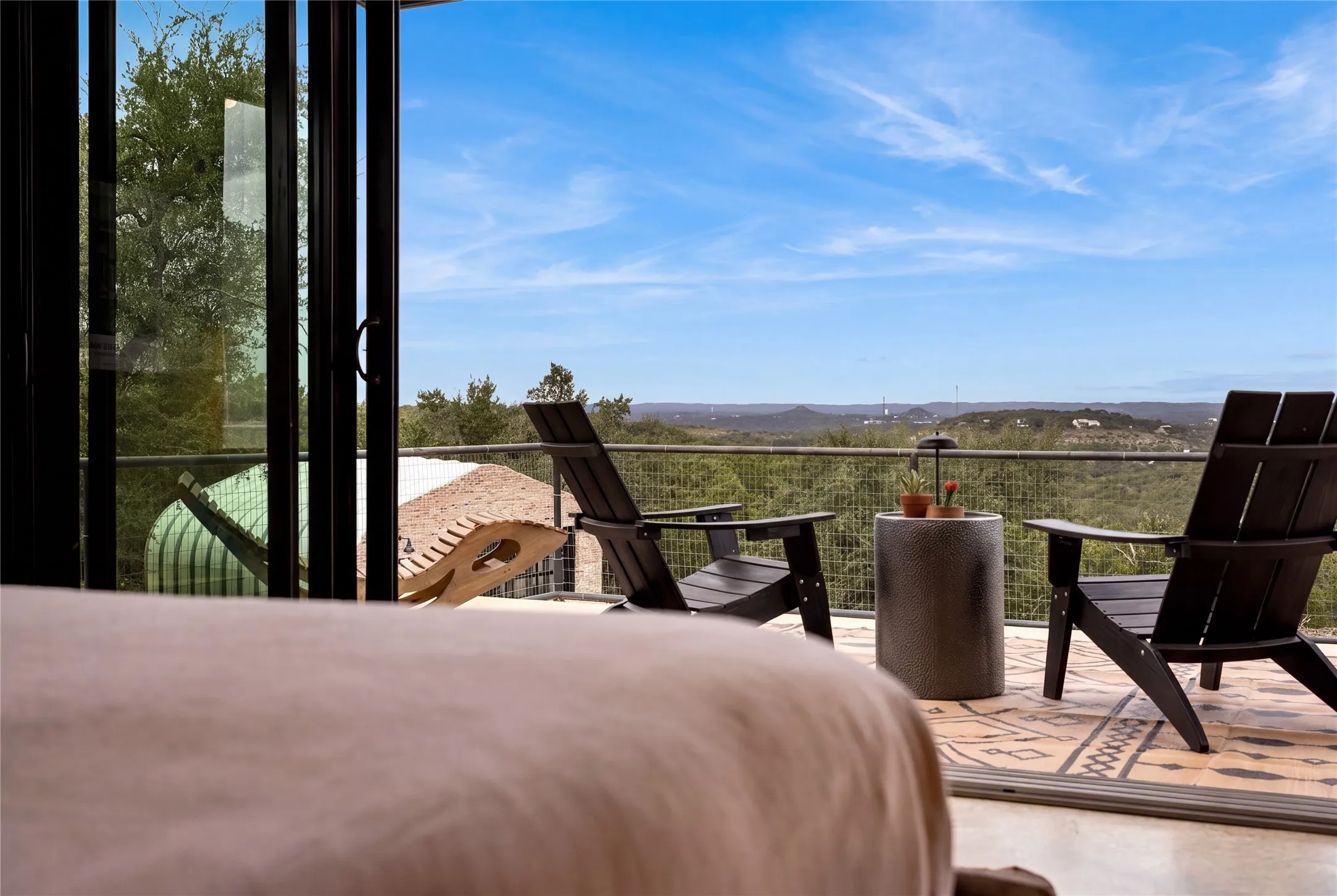 Floor-to-ceiling glass doors open directly to a private balcony overlooking rolling hills.
