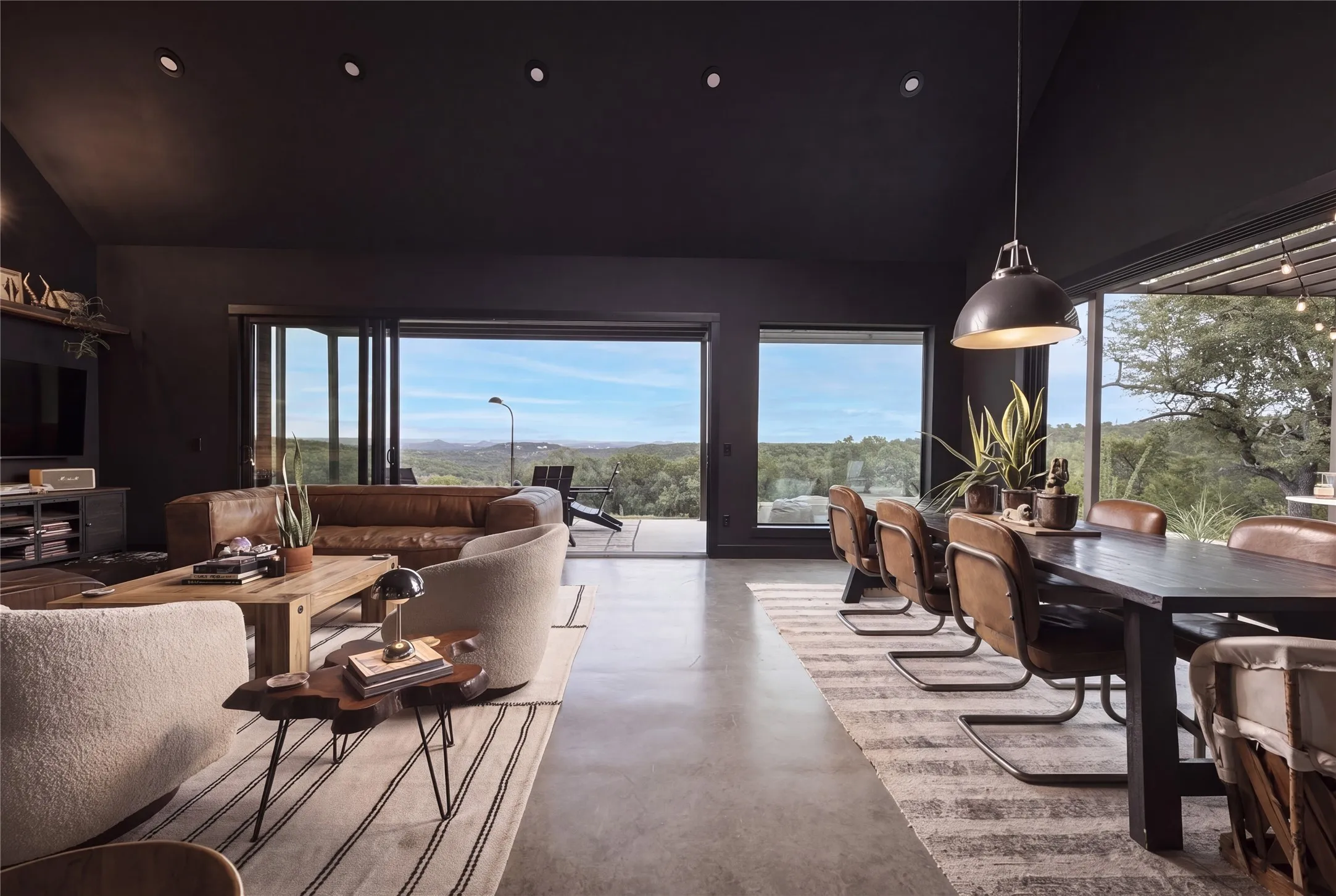 Gleaming concrete floors and dramatic dark walls frame expansive hillsides seen through glass walls.