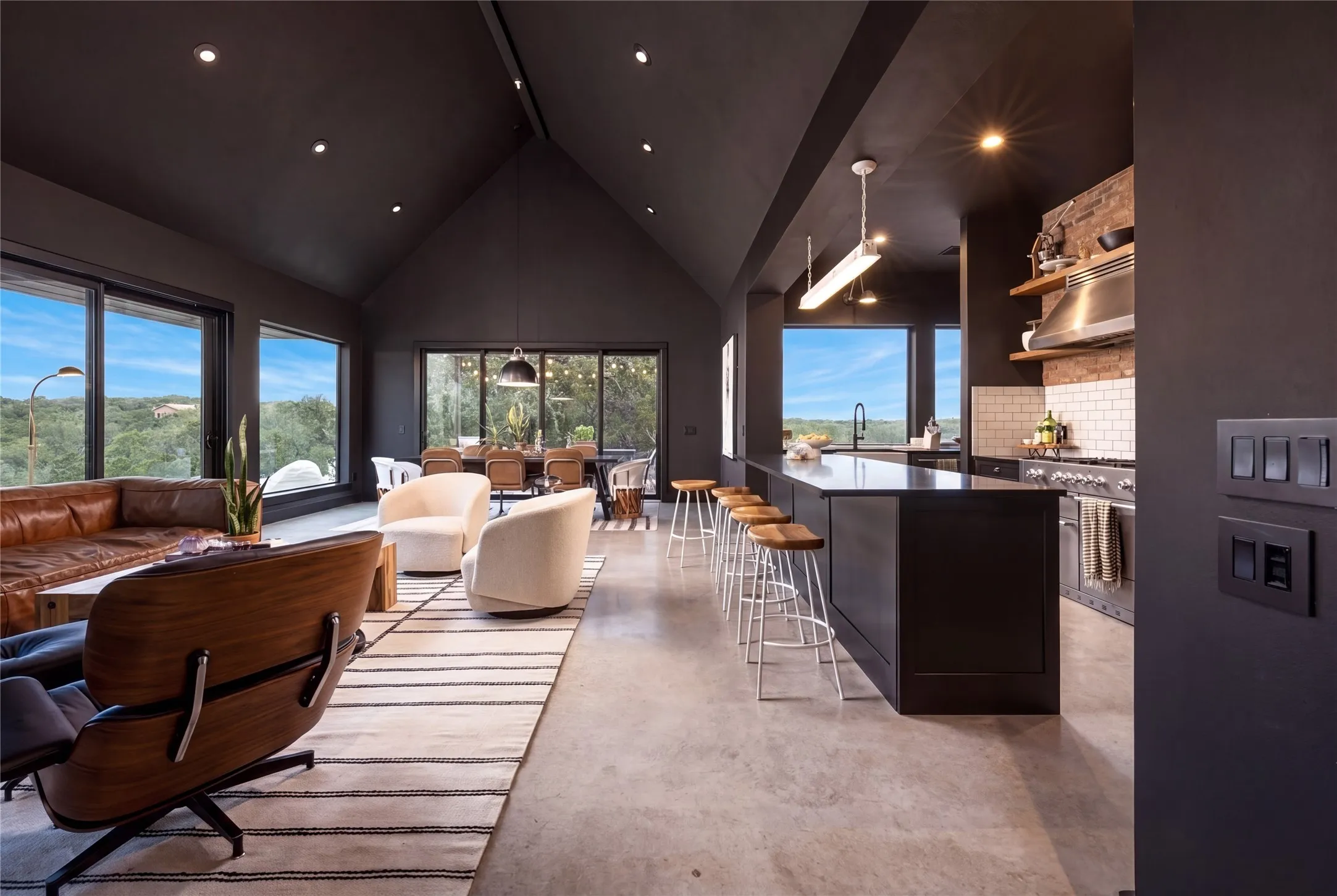 Gleaming concrete floors and vaulted ceilings define this contemporary open living and kitchen space.