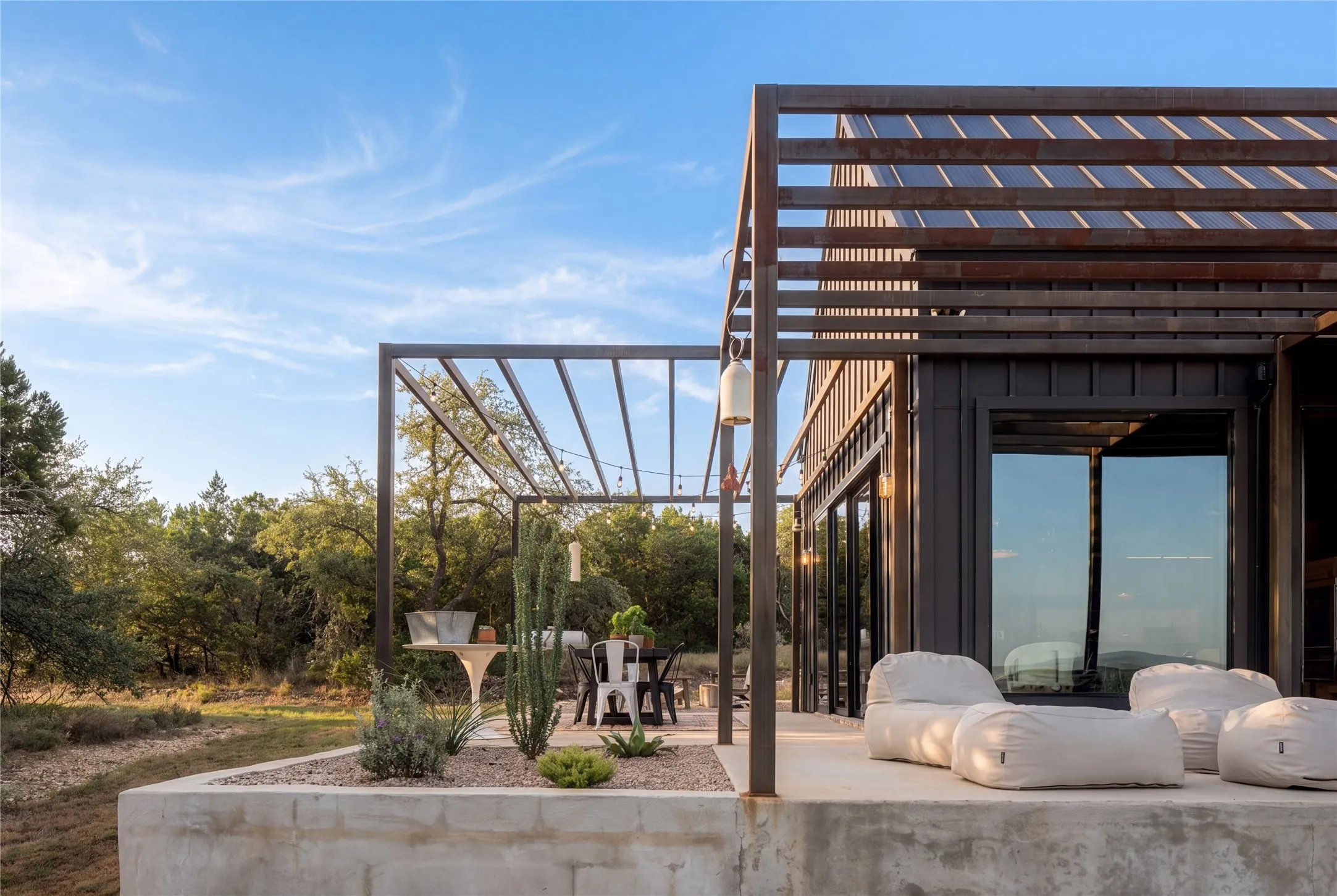 Clean lines and a modern metal pergola define this raised concrete terrace.