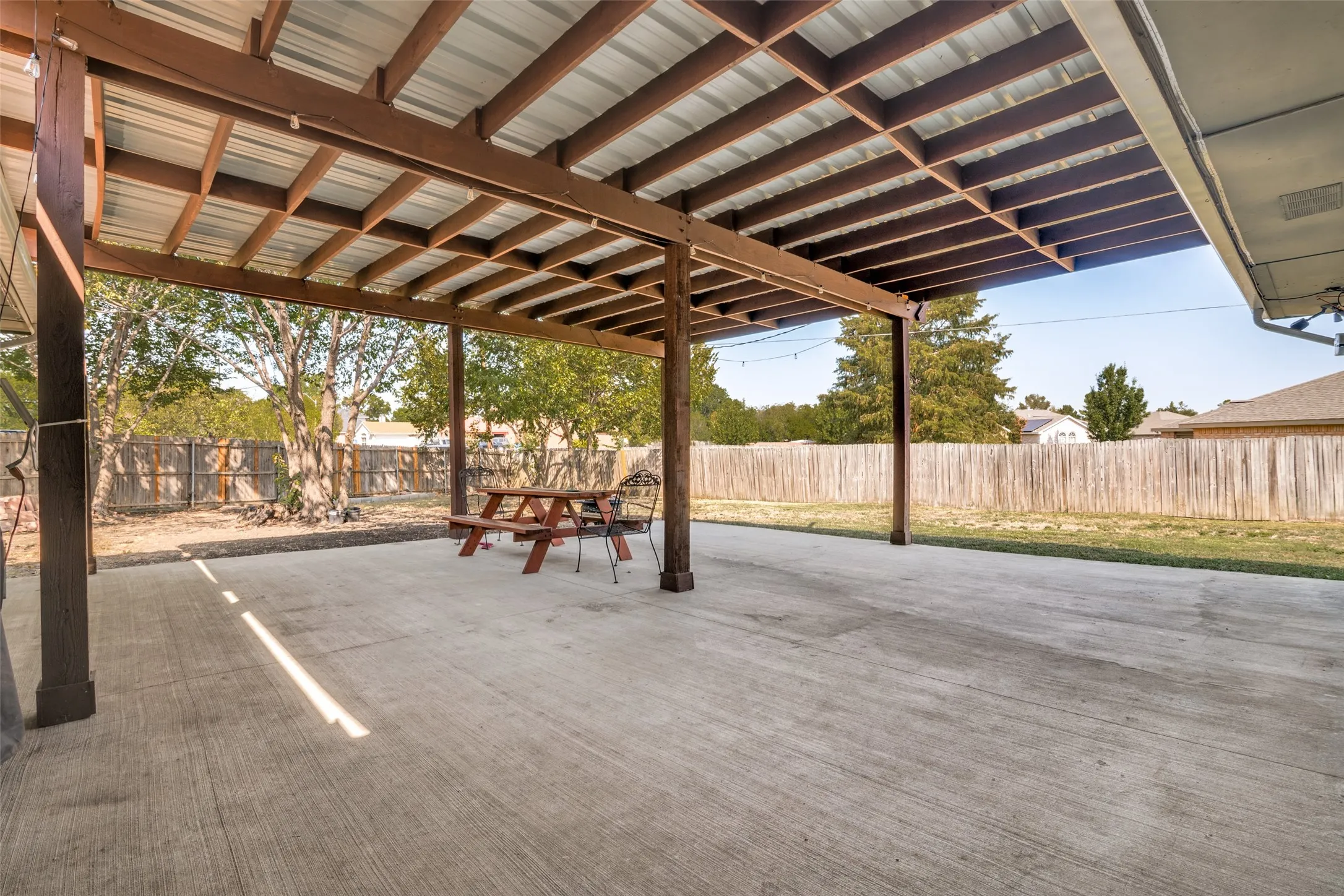 Expansive covered concrete patio with a metal roof and exposed wood beams