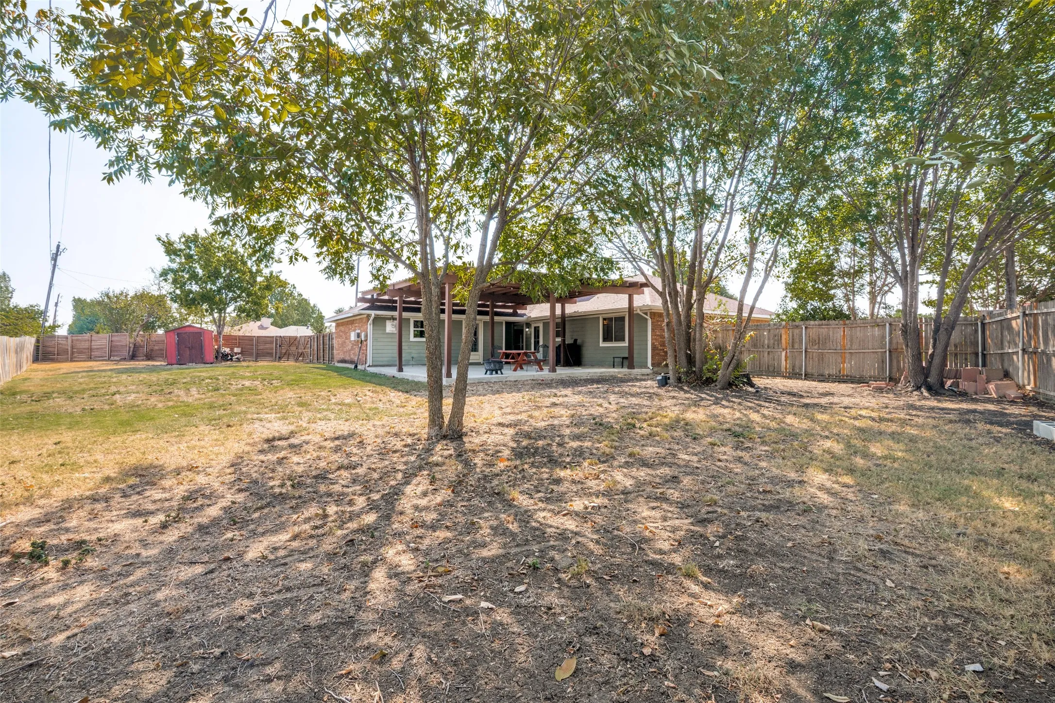 Expansive backyard featuring a covered patio, and mature trees.