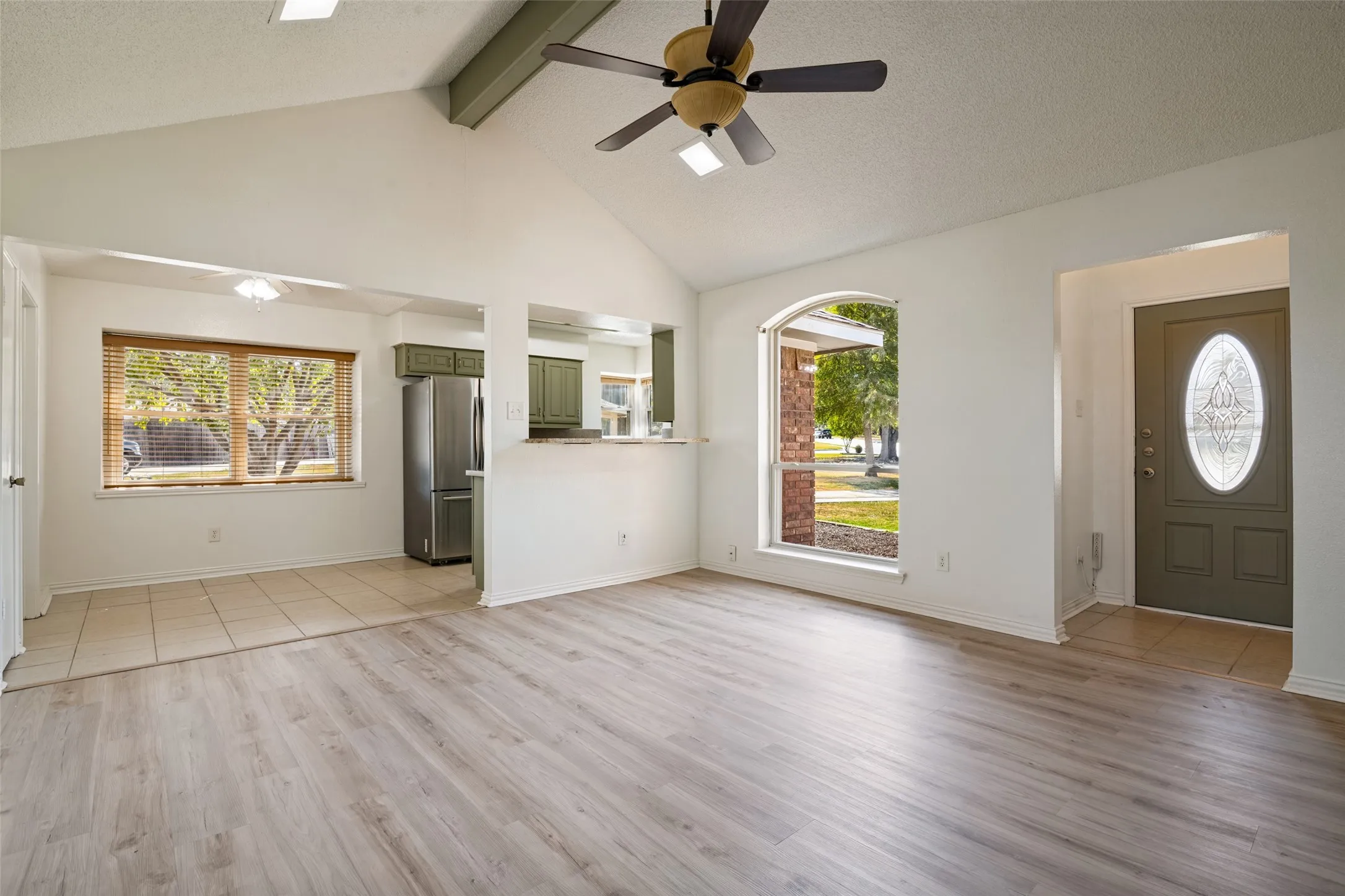 Vaulted ceiling with exposed beam, wood-finish flooring, arched window.