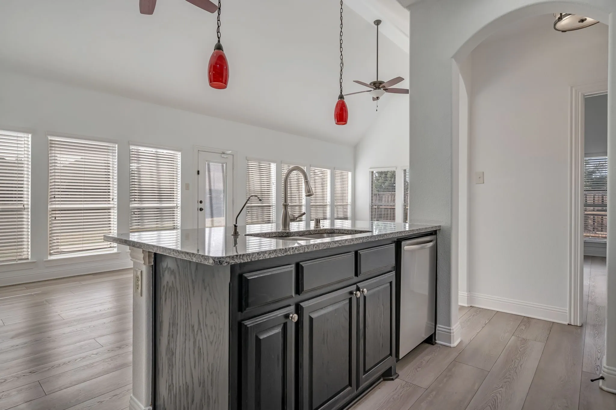Kitchen island with dark cabinetry and a stone-finish countertop, featuring an undermount sink and a stainless steel dishwasher
