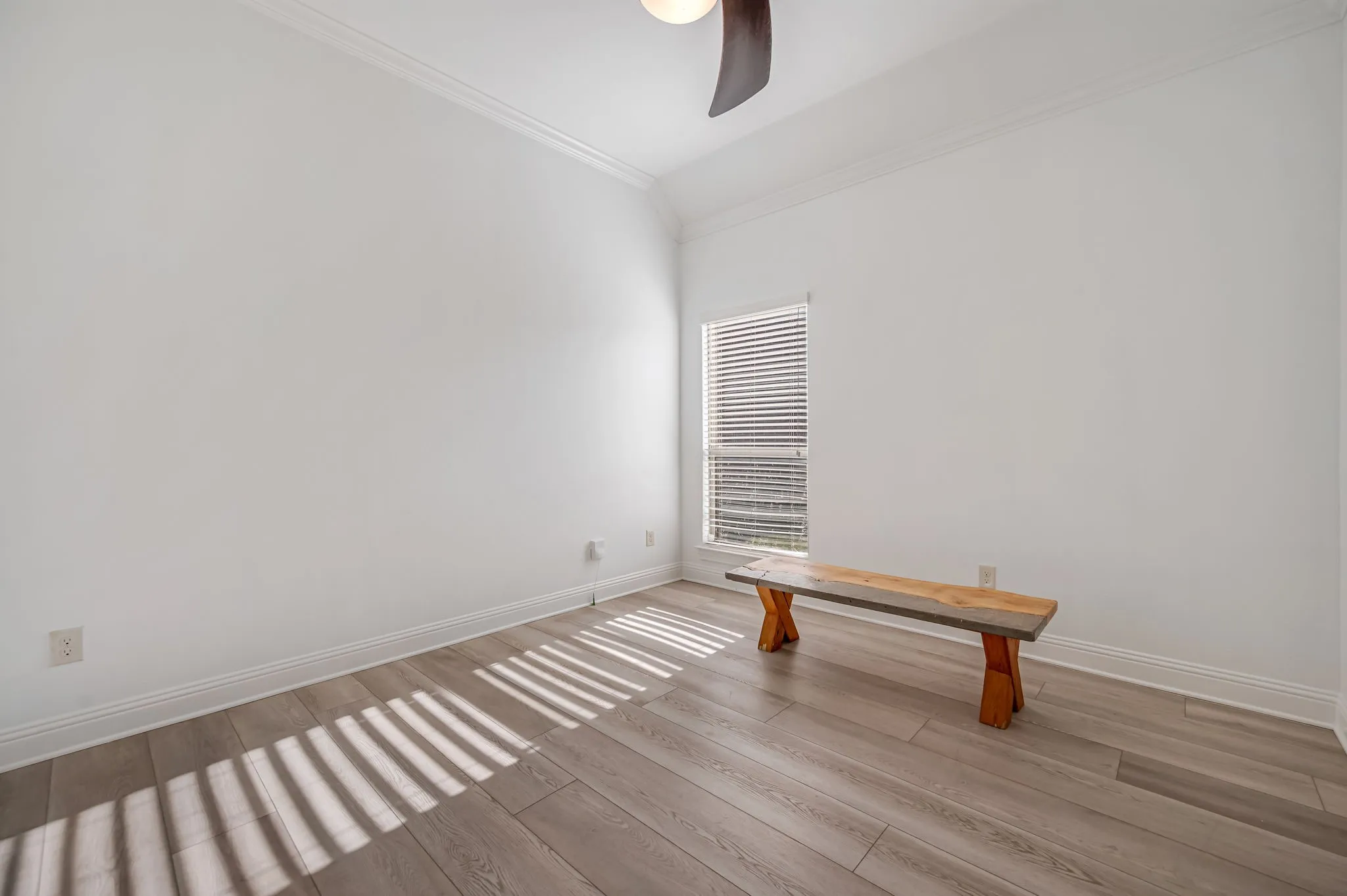 Wood-finish flooring, crown molding, and a window with blinds
