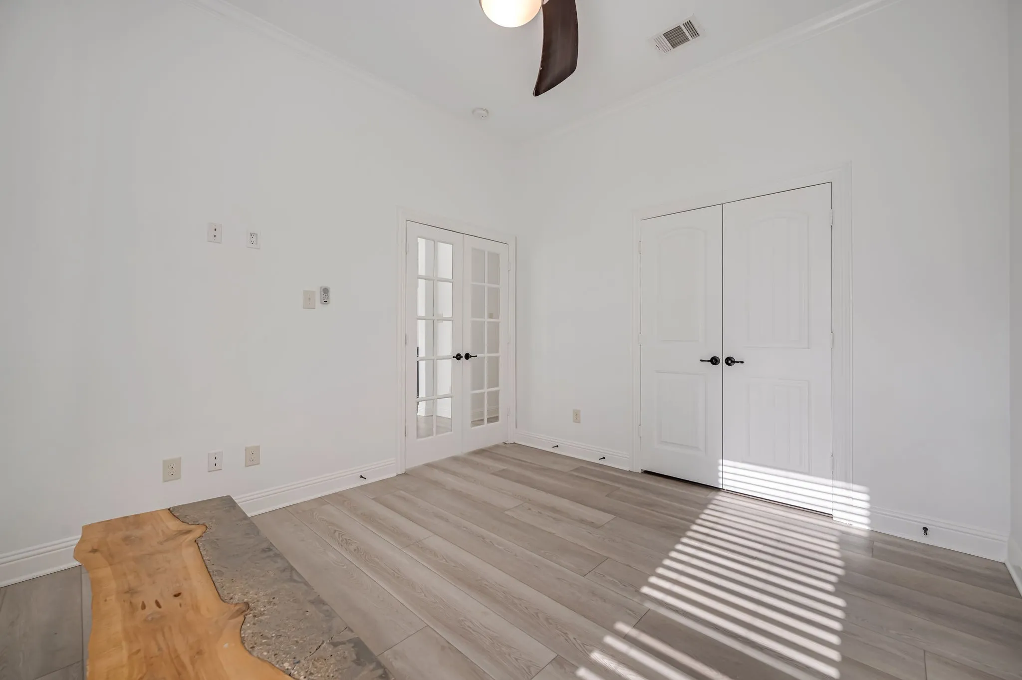 White walls with crown molding, wood-finish flooring, and a ceiling fan