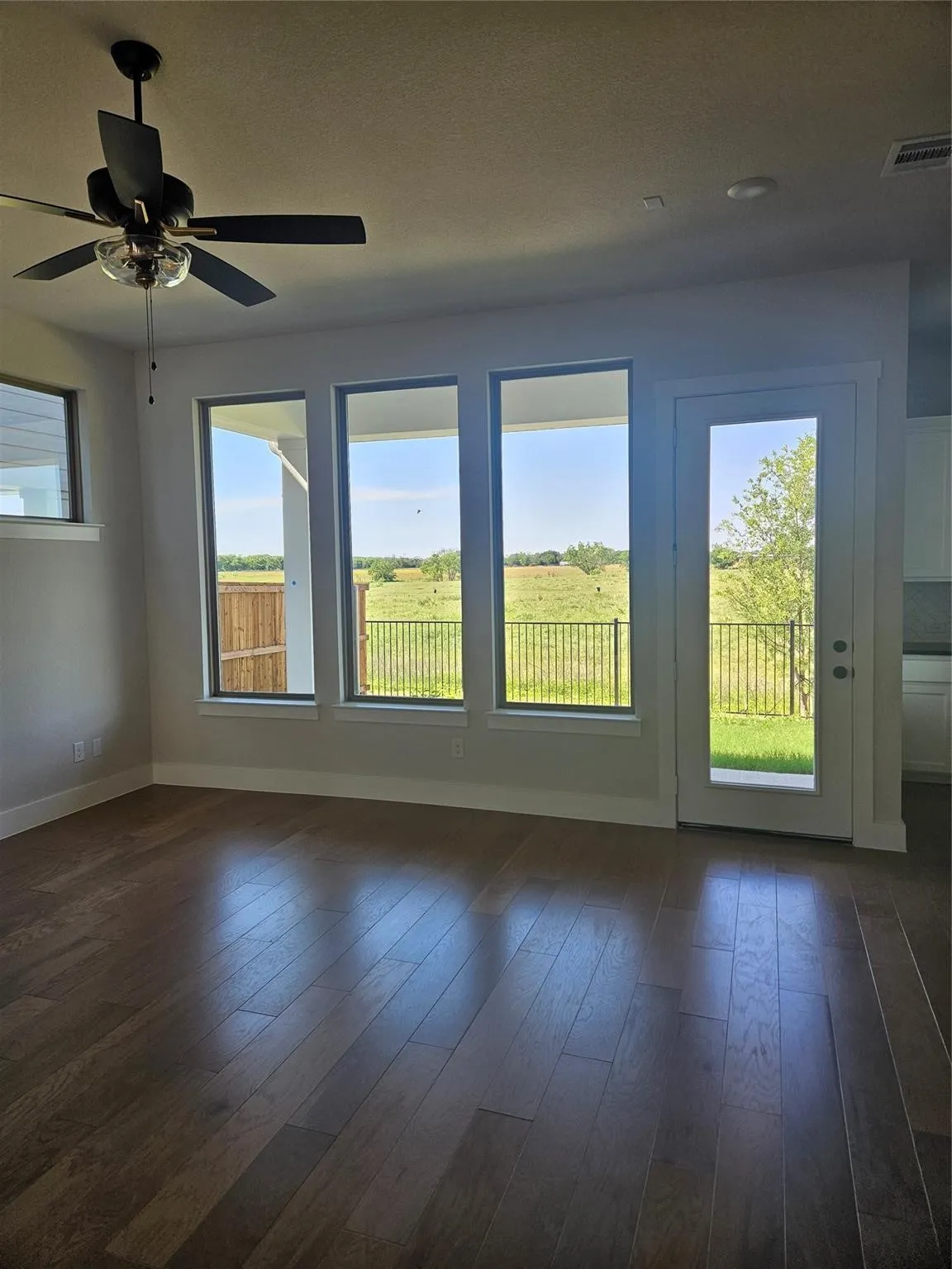 Wood-finish flooring, multiple windows, ceiling fan, glass-panel door, and recessed lighting