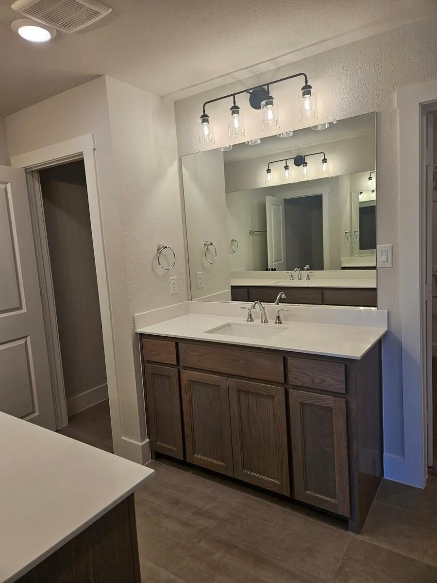 Dual wood-finish vanities with light-toned countertops and integrated sinks