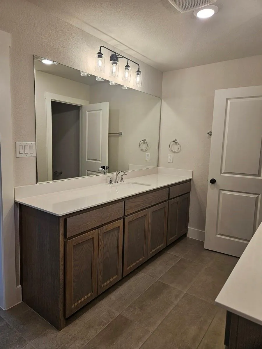 Double vanity with light wood-finish cabinetry and white countertops