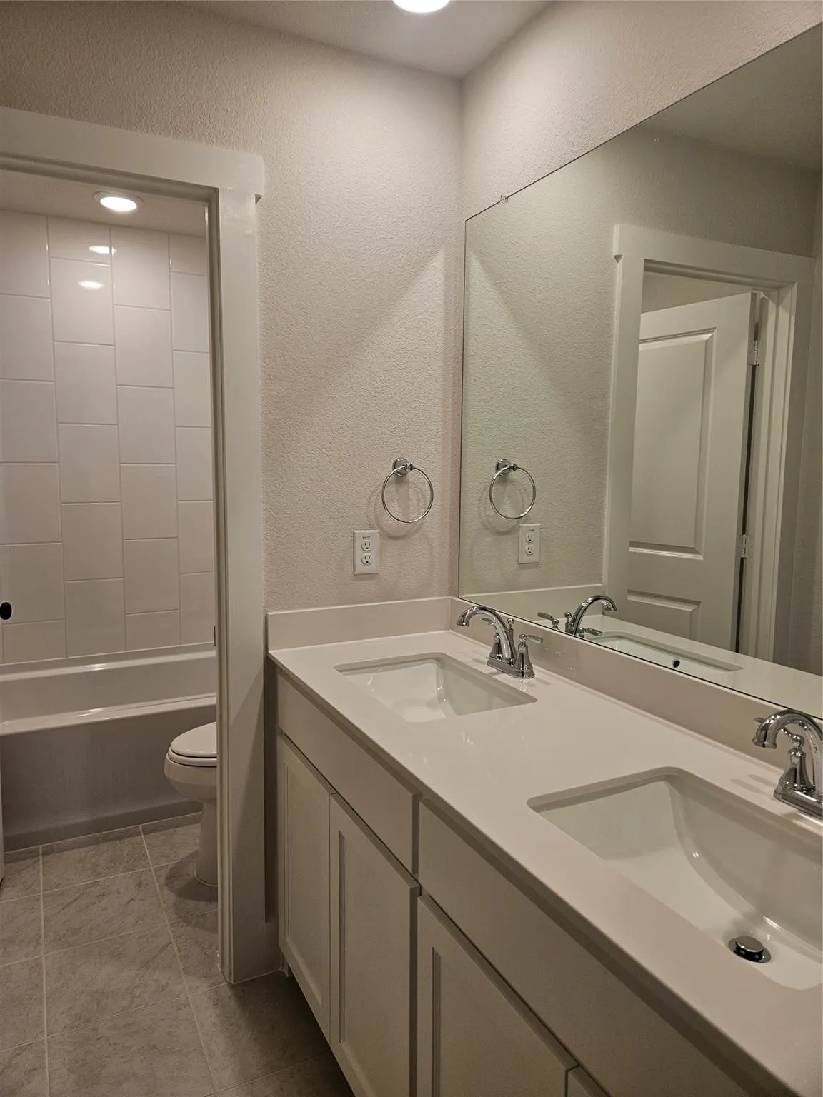 Dual vanity with integral sinks, light-toned countertops, and chrome fixtures
