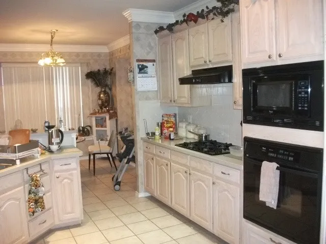 White cabinetry with silver-tone hardware, white tile flooring, built-in microwave, and oven