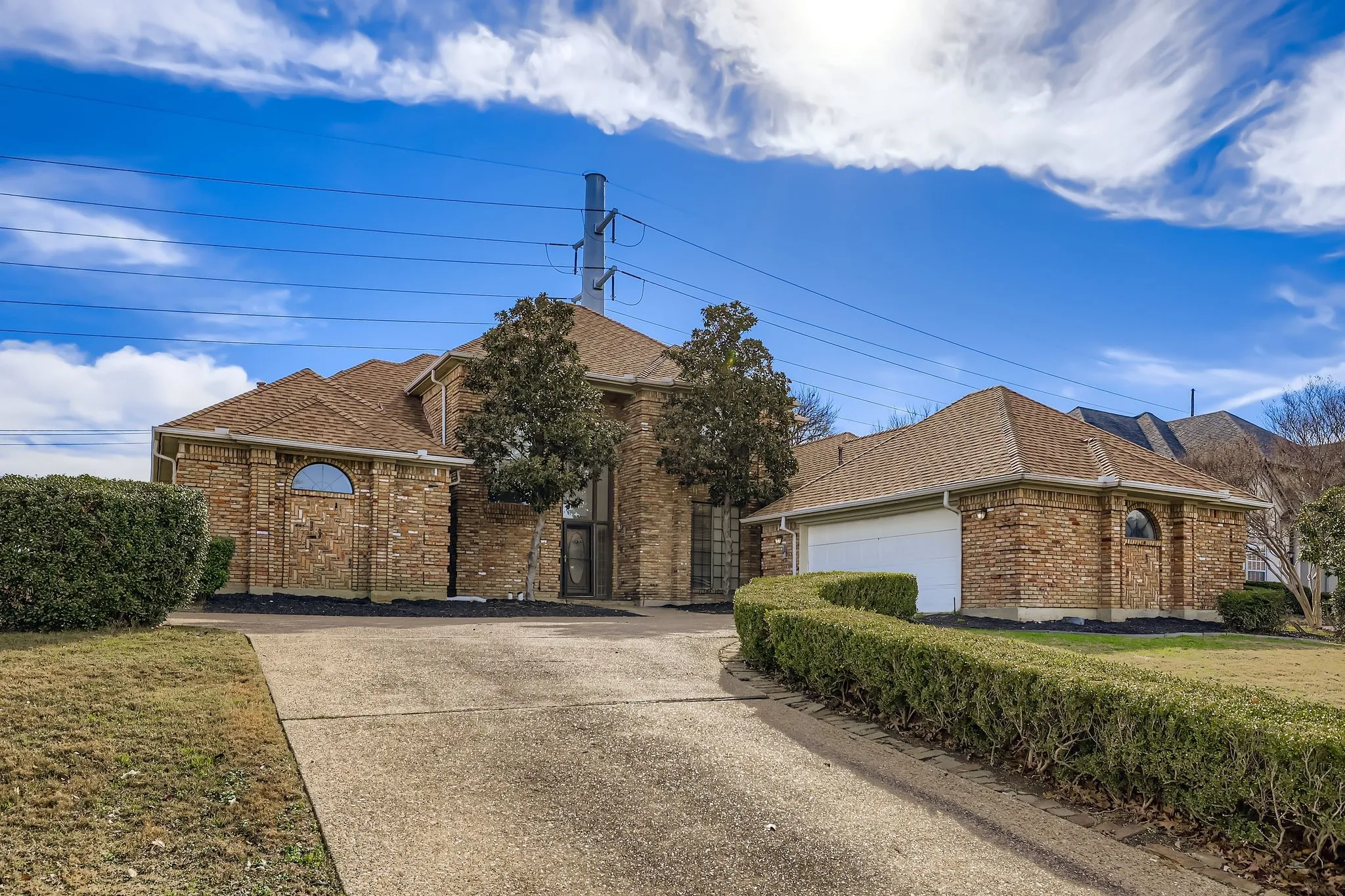Brick exterior with arched windows, attached garage, and a concrete driveway
