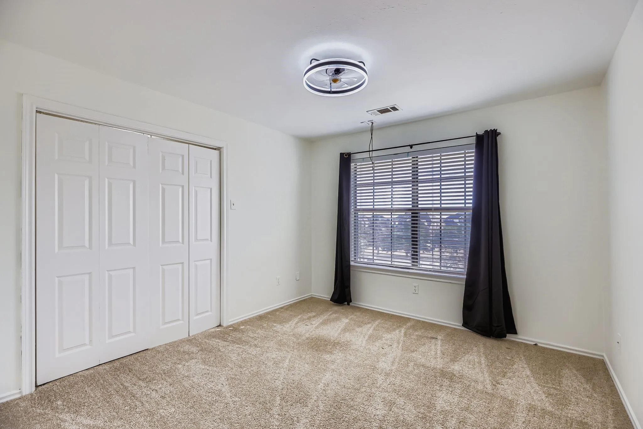Neutral wall tones with a window featuring blinds and dark drapes
