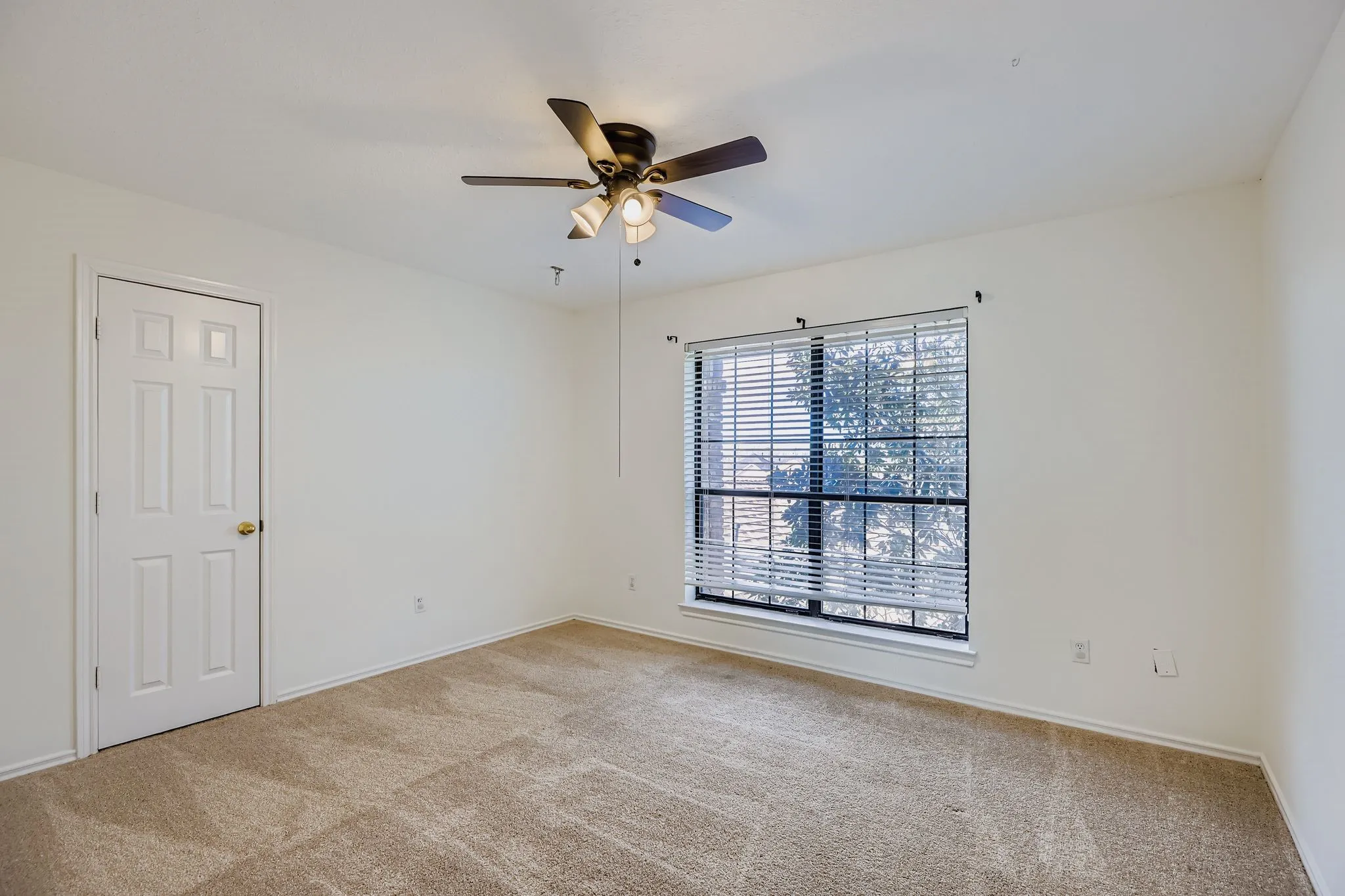 Neutral wall finishes, carpeted flooring, window with blinds, and a ceiling fan with integrated lighting