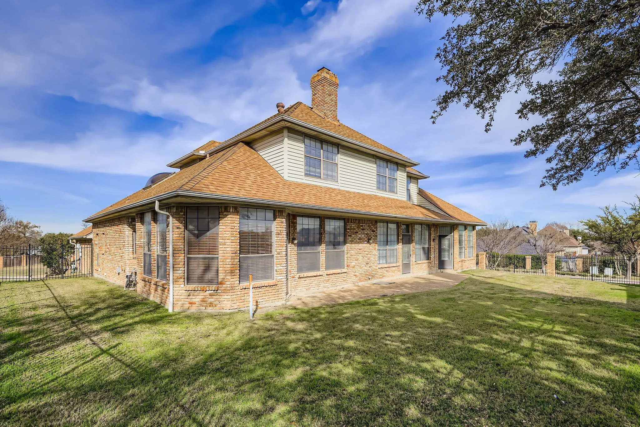Brick exterior with a shingle roof and multiple windows