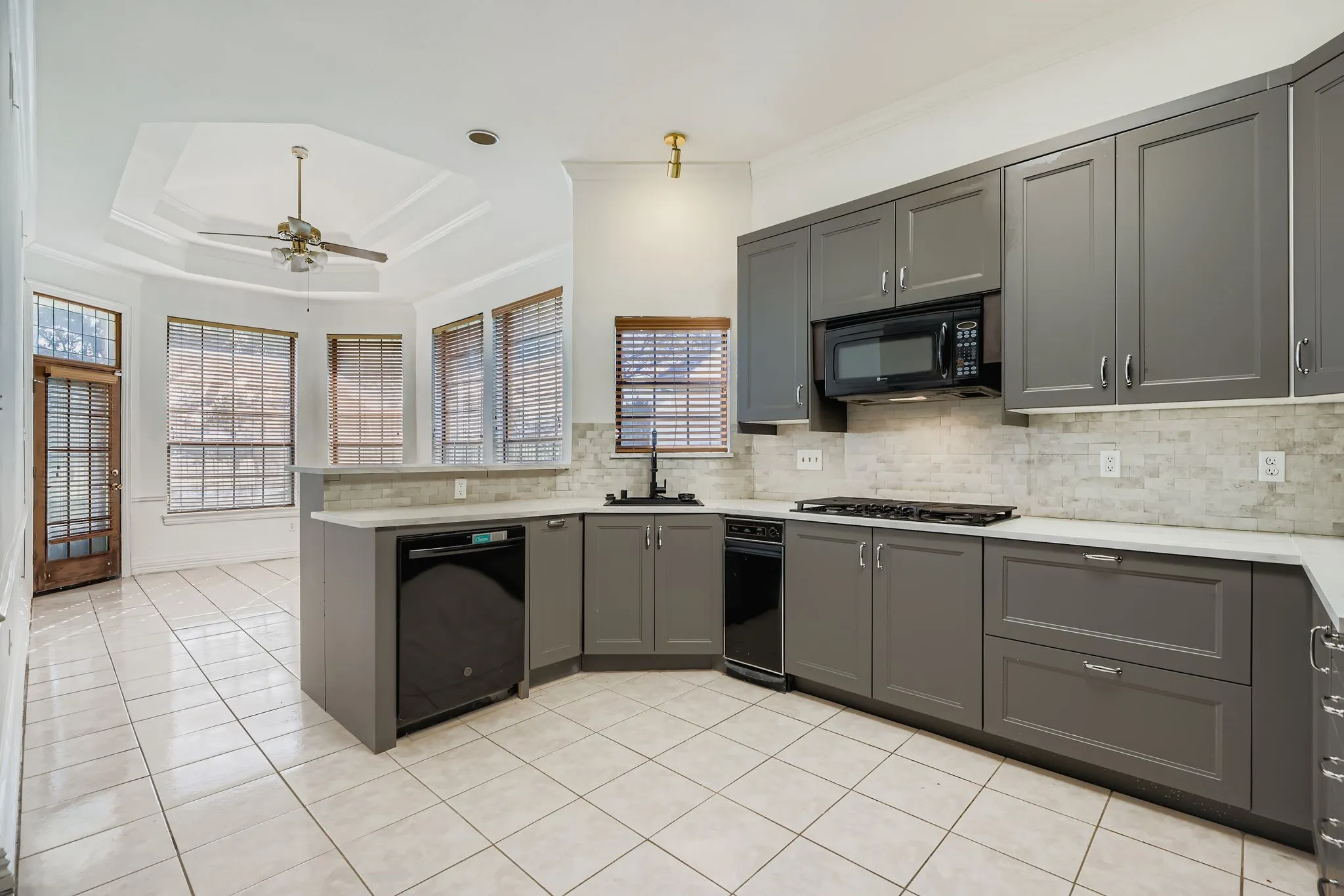 Kitchen featuring grey cabinetry, white countertops, tile flooring, and a tile backsplash