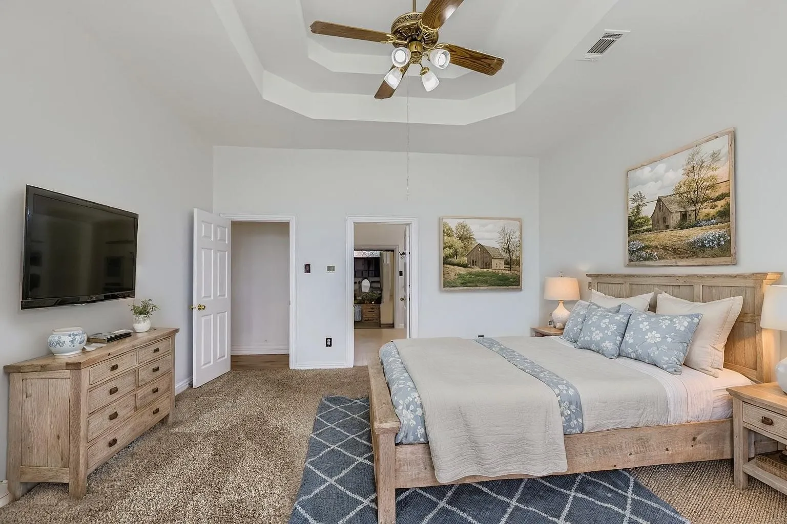 Tray ceiling with a ceiling fan, light-colored walls, and carpeting
