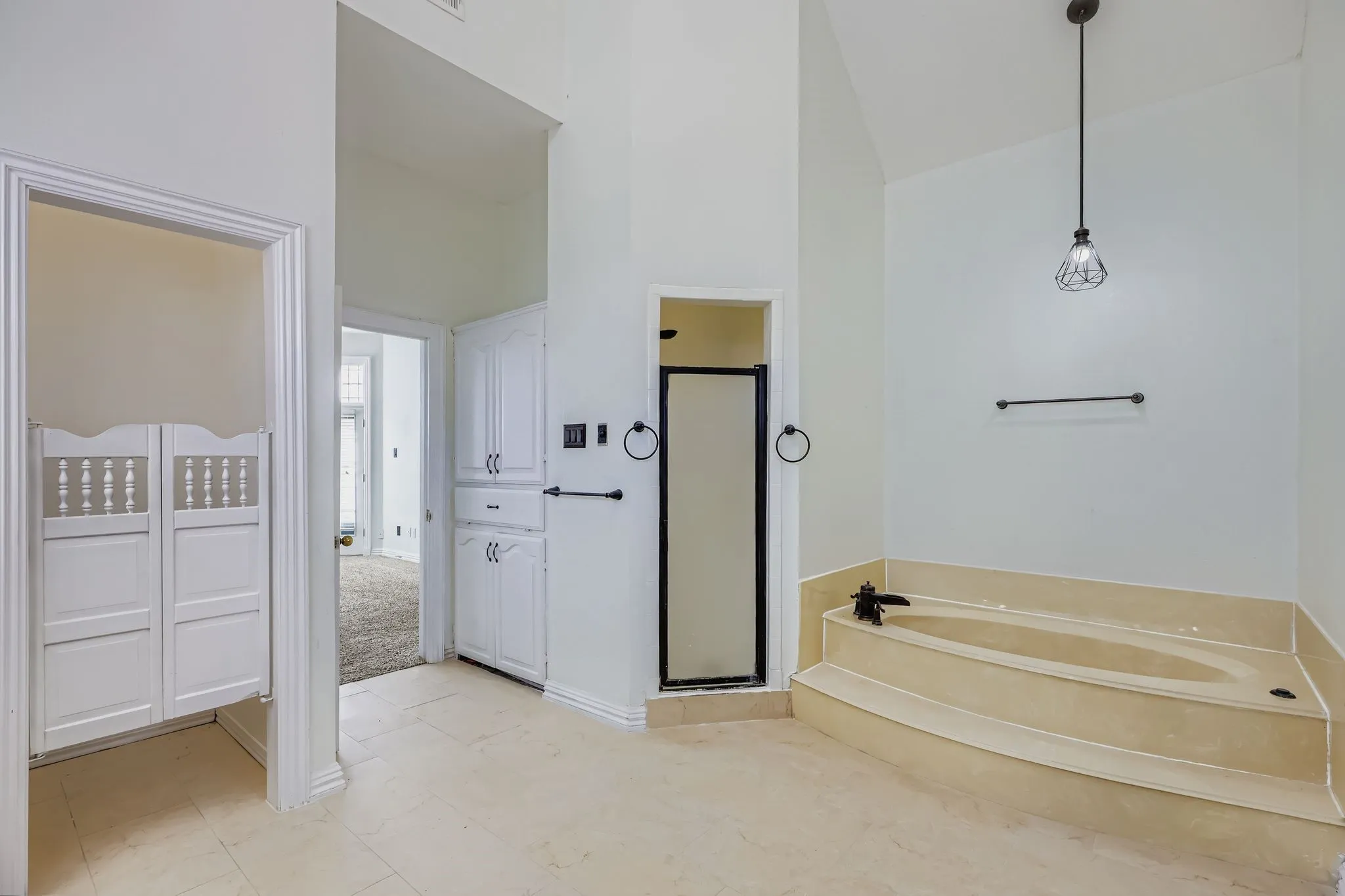 Soaking tub with stepped surround, glass-enclosed shower, built-in storage cabinetry, and tiled flooring