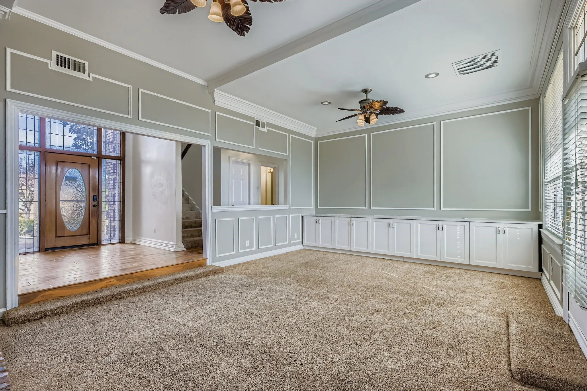 Built-in cabinetry, recessed lighting, ceiling fans, decorative wall molding, and wood-finish flooring at entry