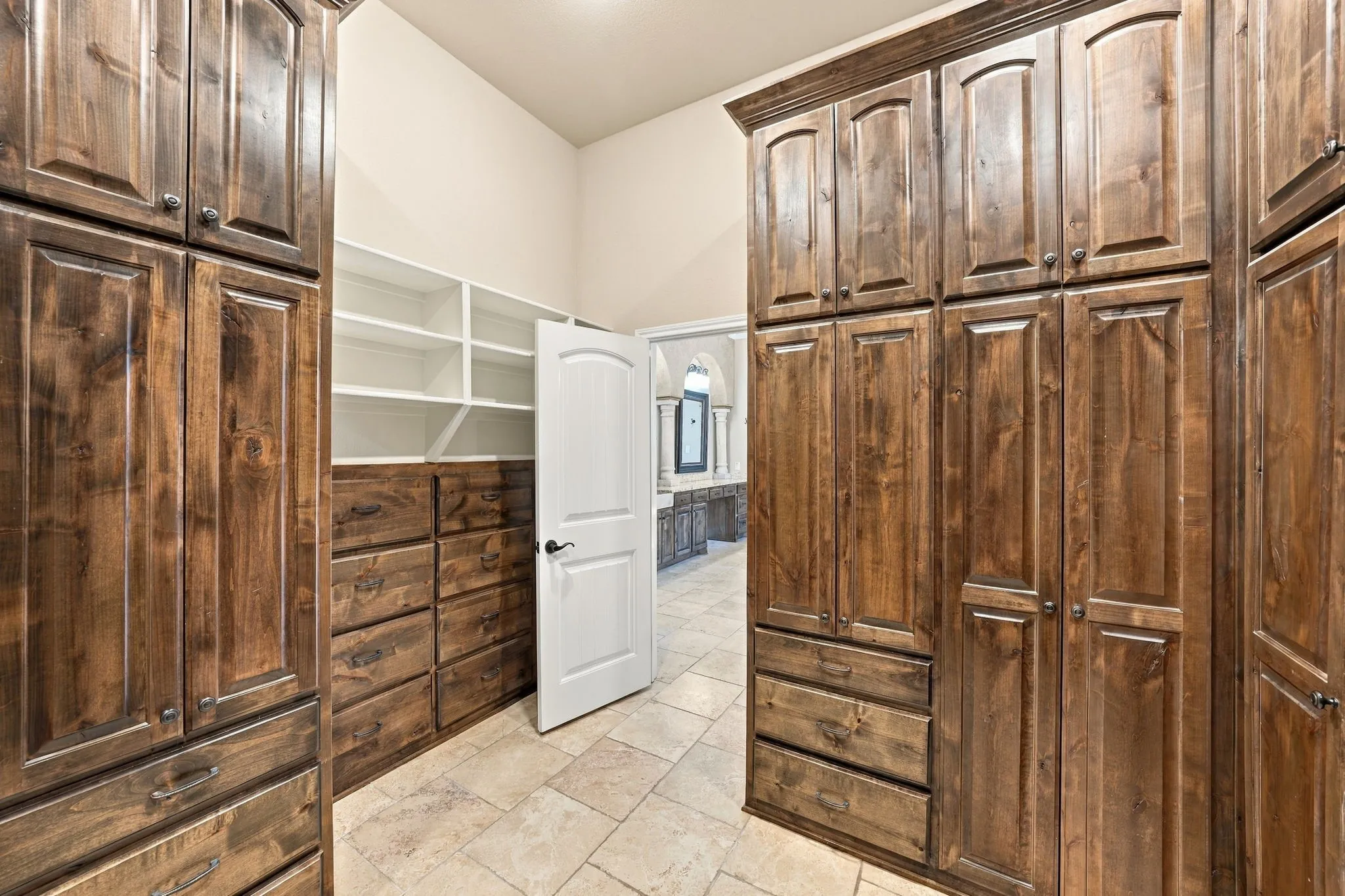 Built-in wood cabinetry, integrated drawers, extensive shelving, arched doorways, and tile flooring
