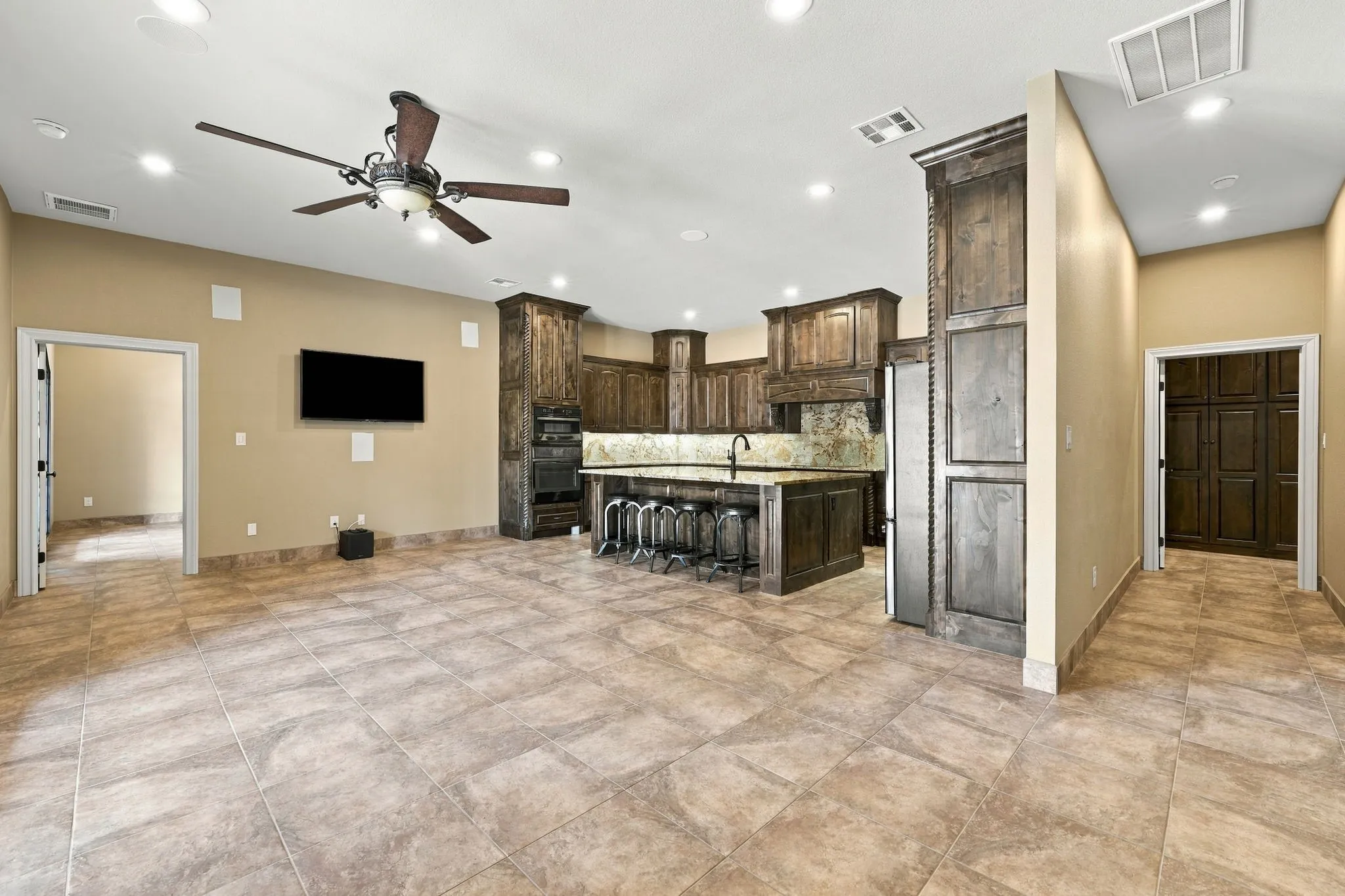 Spacious open-concept living area featuring tile flooring, recessed lighting, and a ceiling fan