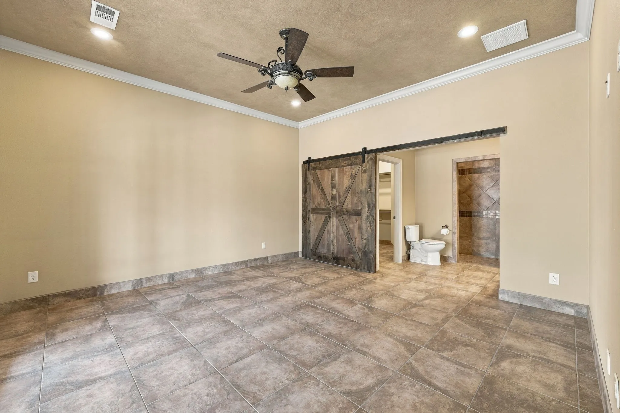 Spacious room featuring tile flooring, crown molding, and a ceiling fan