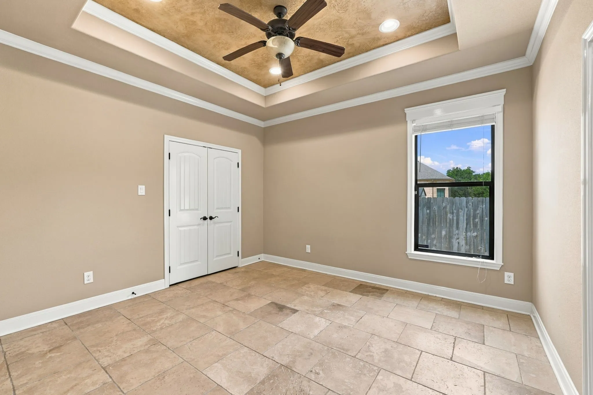 Tray ceiling with recessed lighting and ceiling fan, neutral wall paint, tile flooring, double interior doors, and a window with blinds