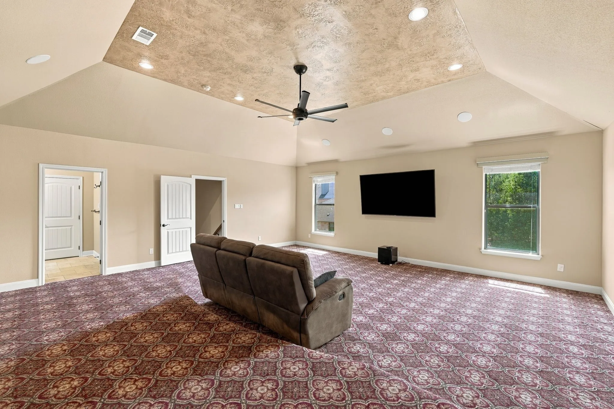 Spacious room with a patterned carpet, recessed lighting, and a ceiling fan