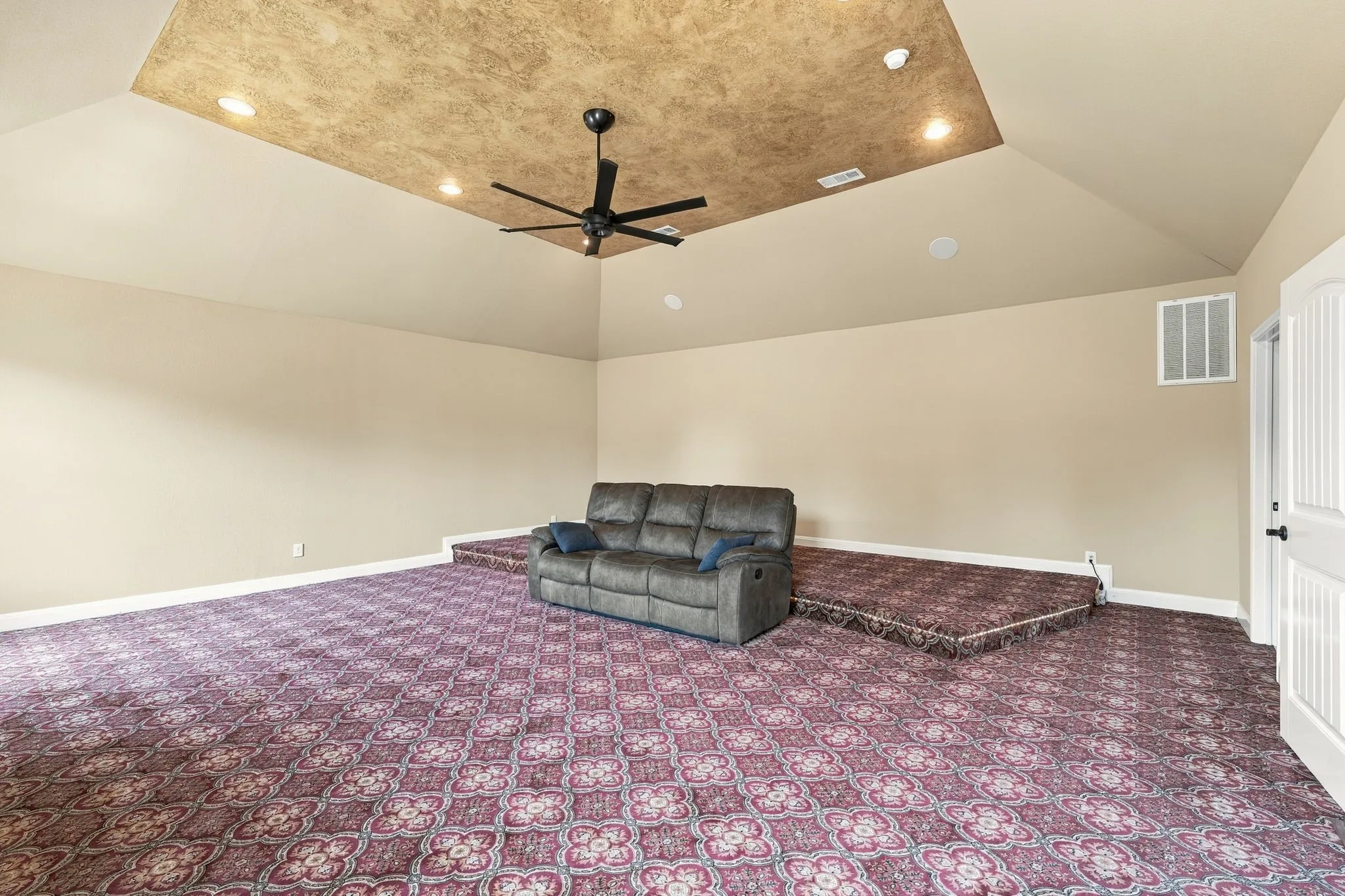Spacious room featuring vaulted ceilings, a decorative ceiling panel, recessed lighting, and patterned carpeting