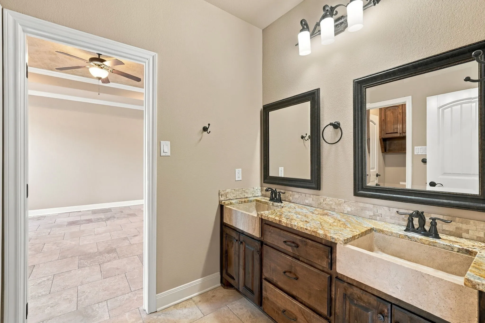 Dual vanity with carved wood cabinetry, stone countertops, and integrated farmhouse sinks
