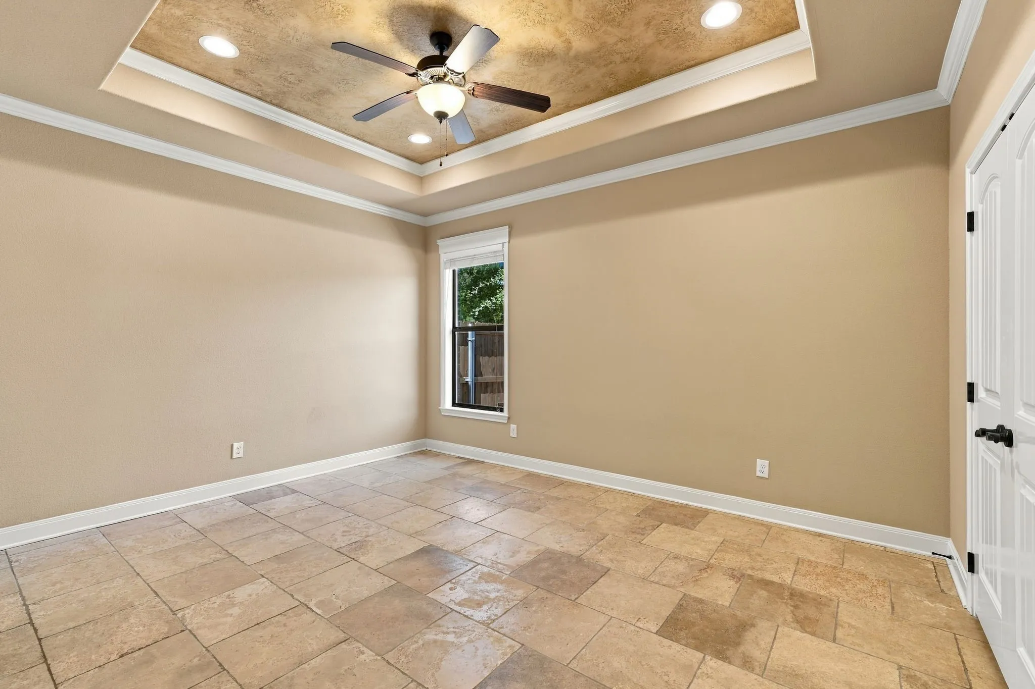 Tray ceiling with textured finish, recessed lighting, and a ceiling fan