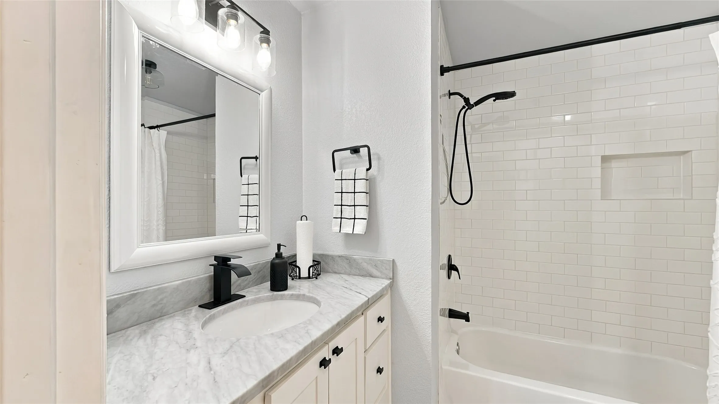 The tub/shower has nice and bright tile with a niche.