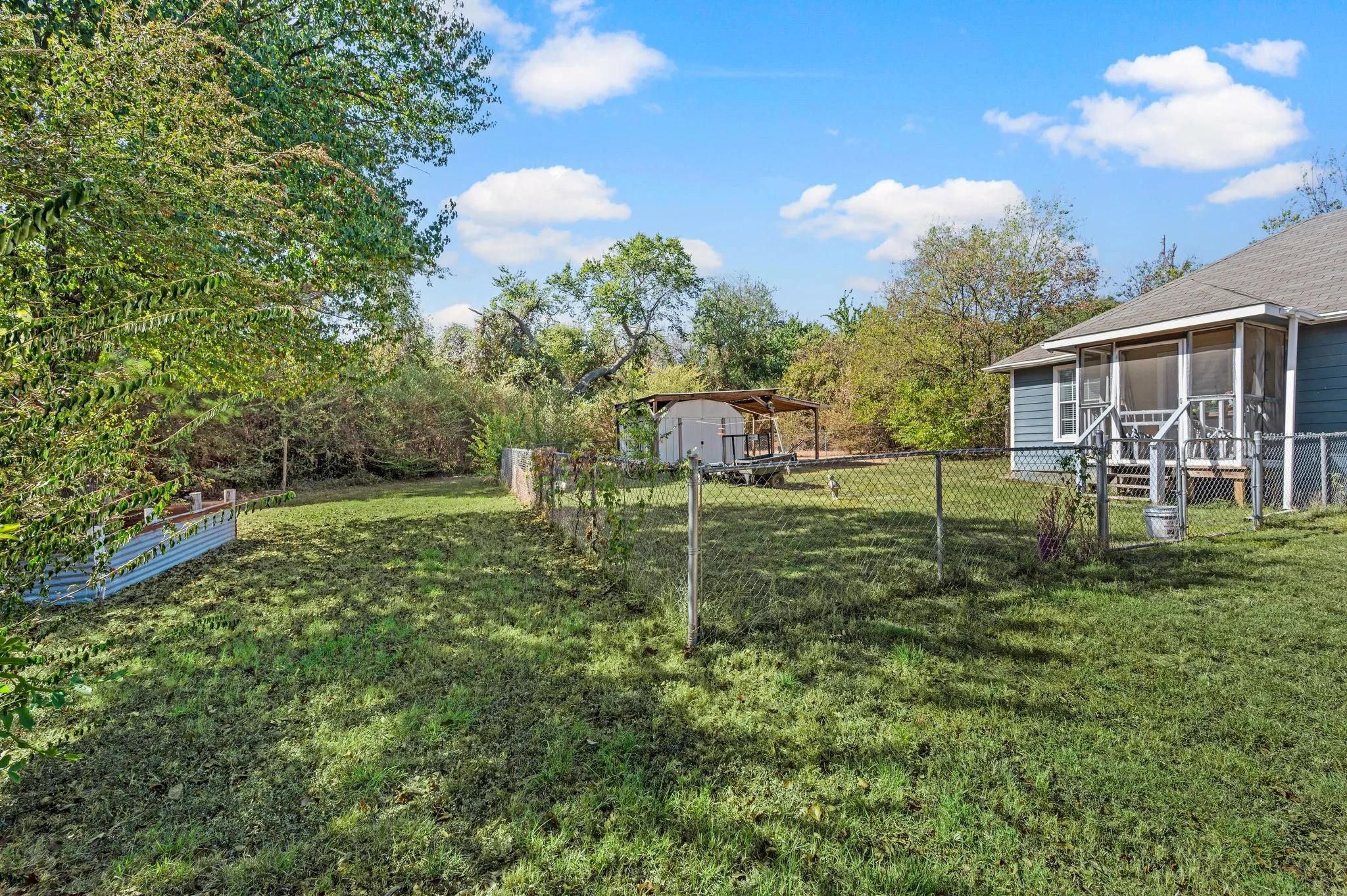 Generous backyard featuring a screened porch, chain-link fencing, a detached shed, and a covered patio structure