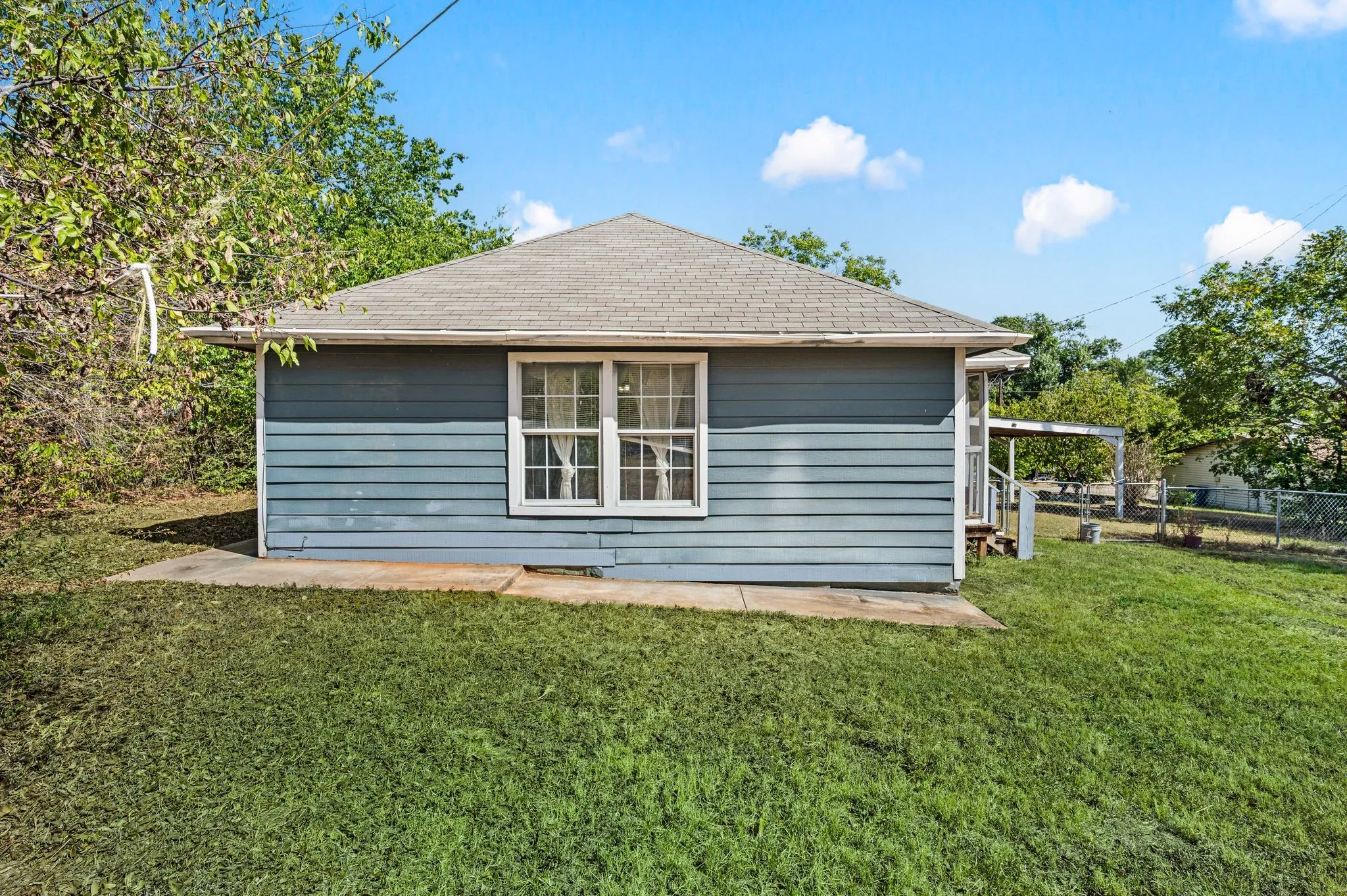 Wood siding exterior, gable roof, double-hung window, concrete foundation, and an expansive lawn