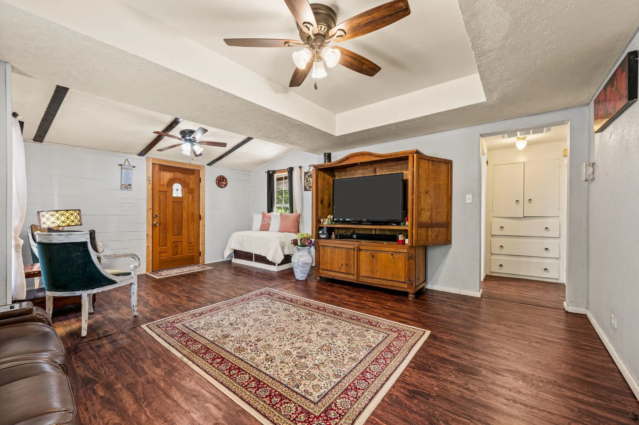  ceiling fan with light fixture, tray ceiling, built-in cabinetry, and paneled wood door