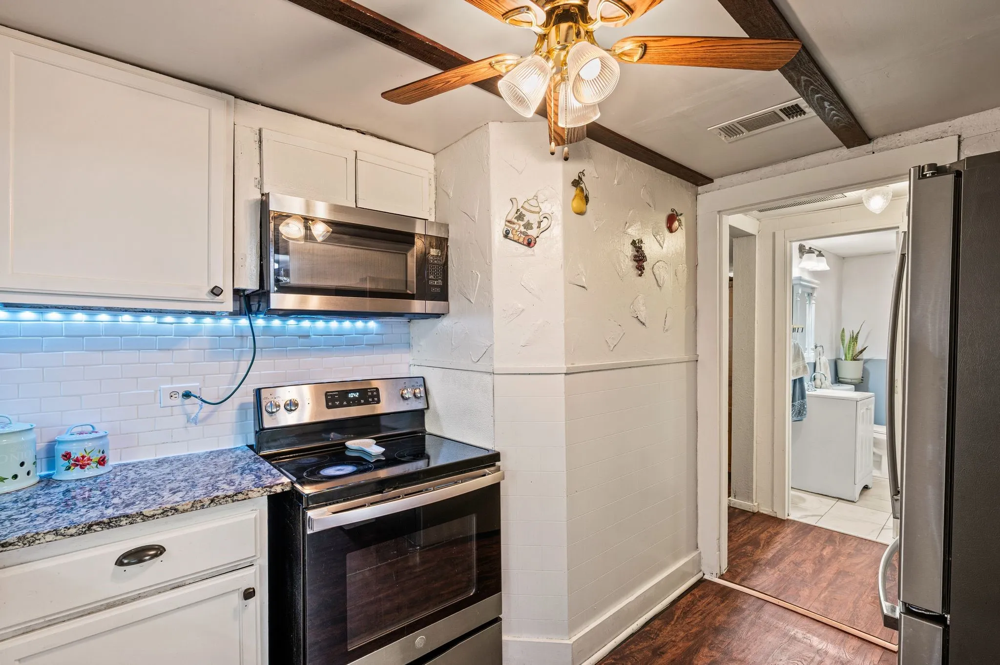 White cabinetry, stainless steel microwave, black glass-top range, granite-finish countertop