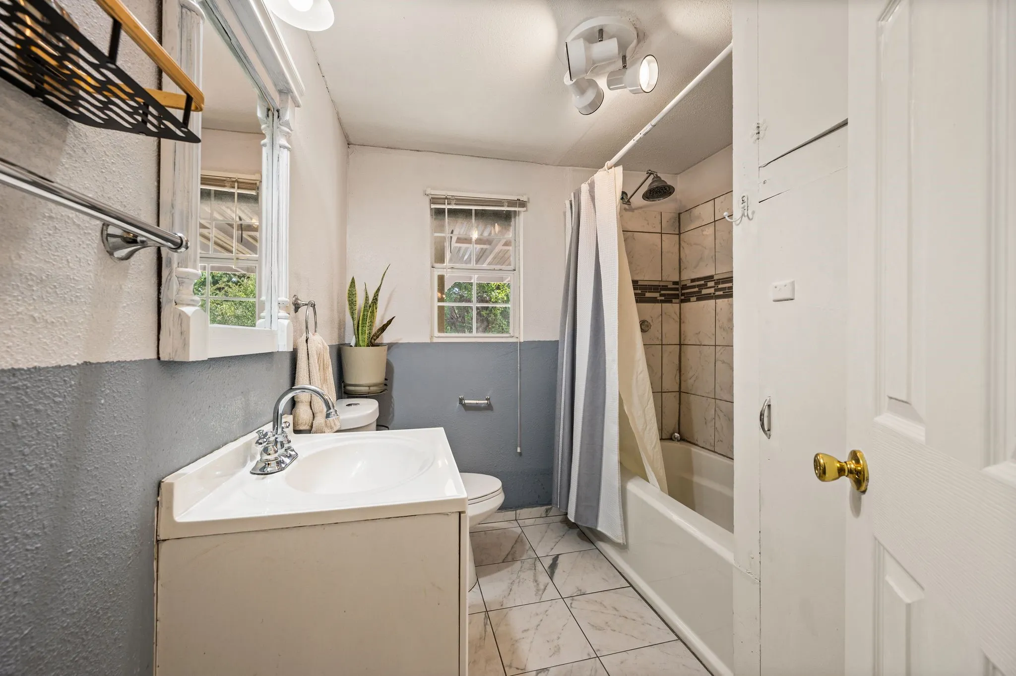 White vanity with an integrated sink, polished chrome faucet, and tiled flooring