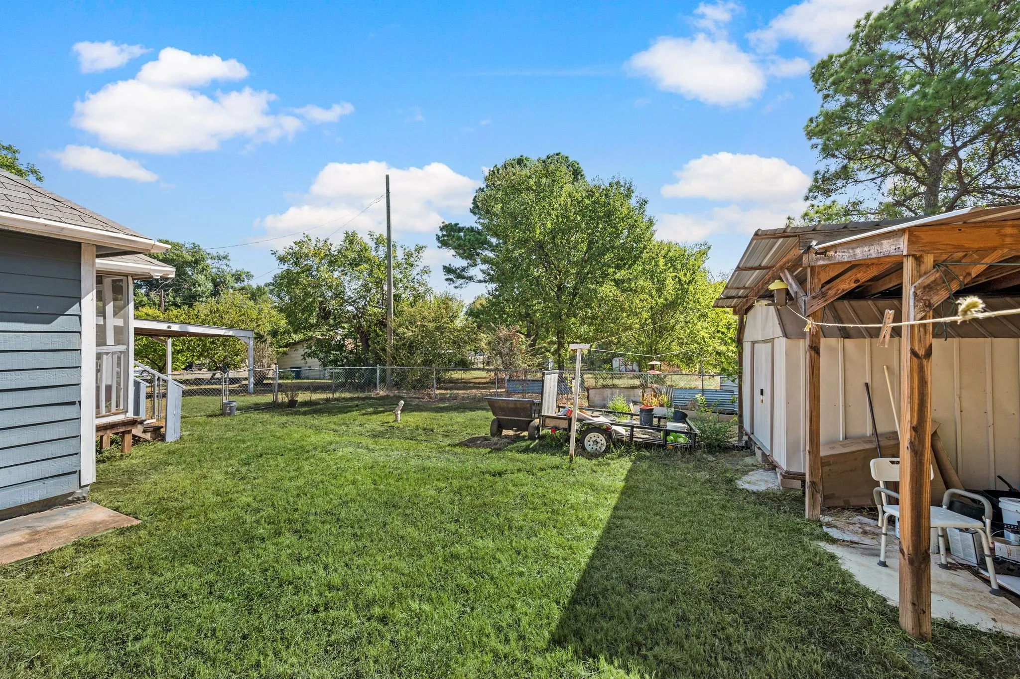 Expansive grassy yard with a detached shed and covered porch