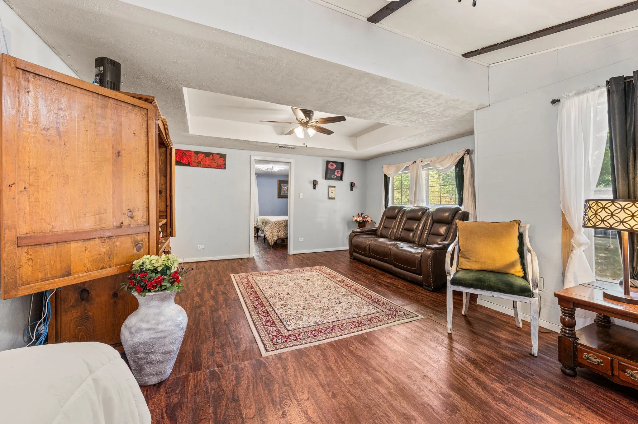  tray ceiling with a ceiling fan, and multiple windows with curtain rods