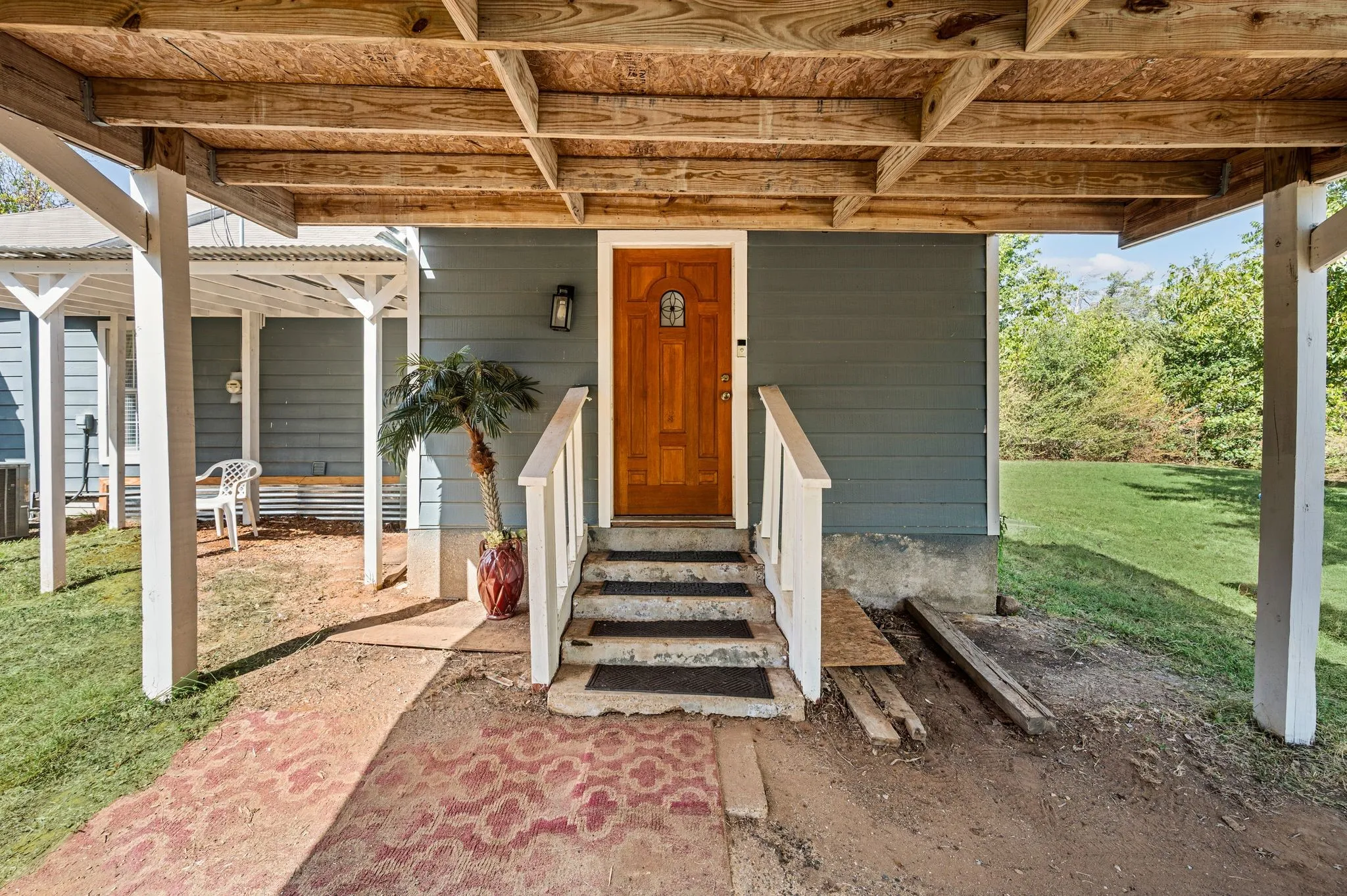 Wood-framed covered entrance with natural wood door and exterior wall sconce