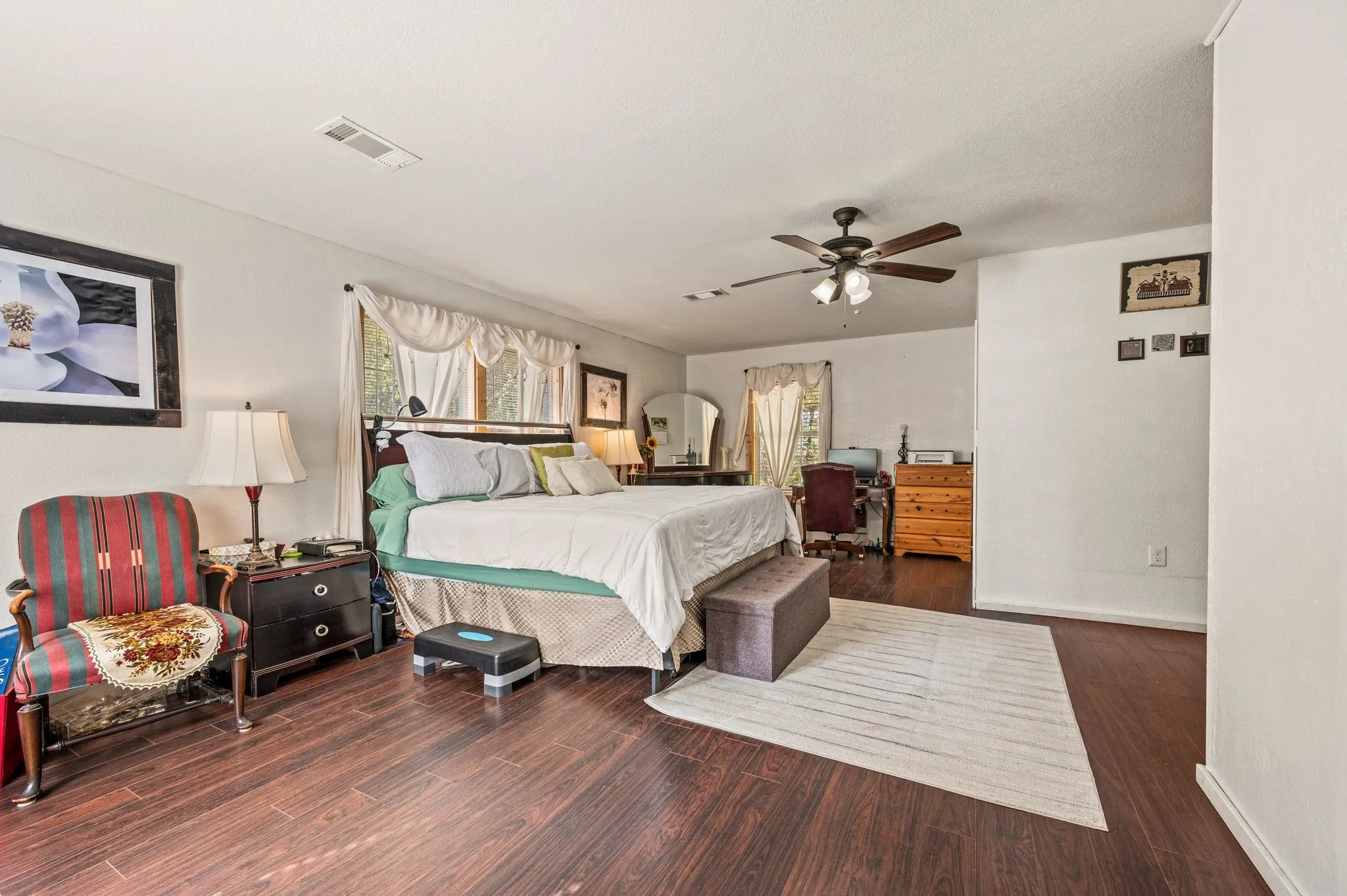 Spacious room featuring a ceiling fan, and multiple windows with drapery
