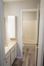 Bathroom with a white vanity featuring a built-in sink, light-toned countertop, and brass hardware