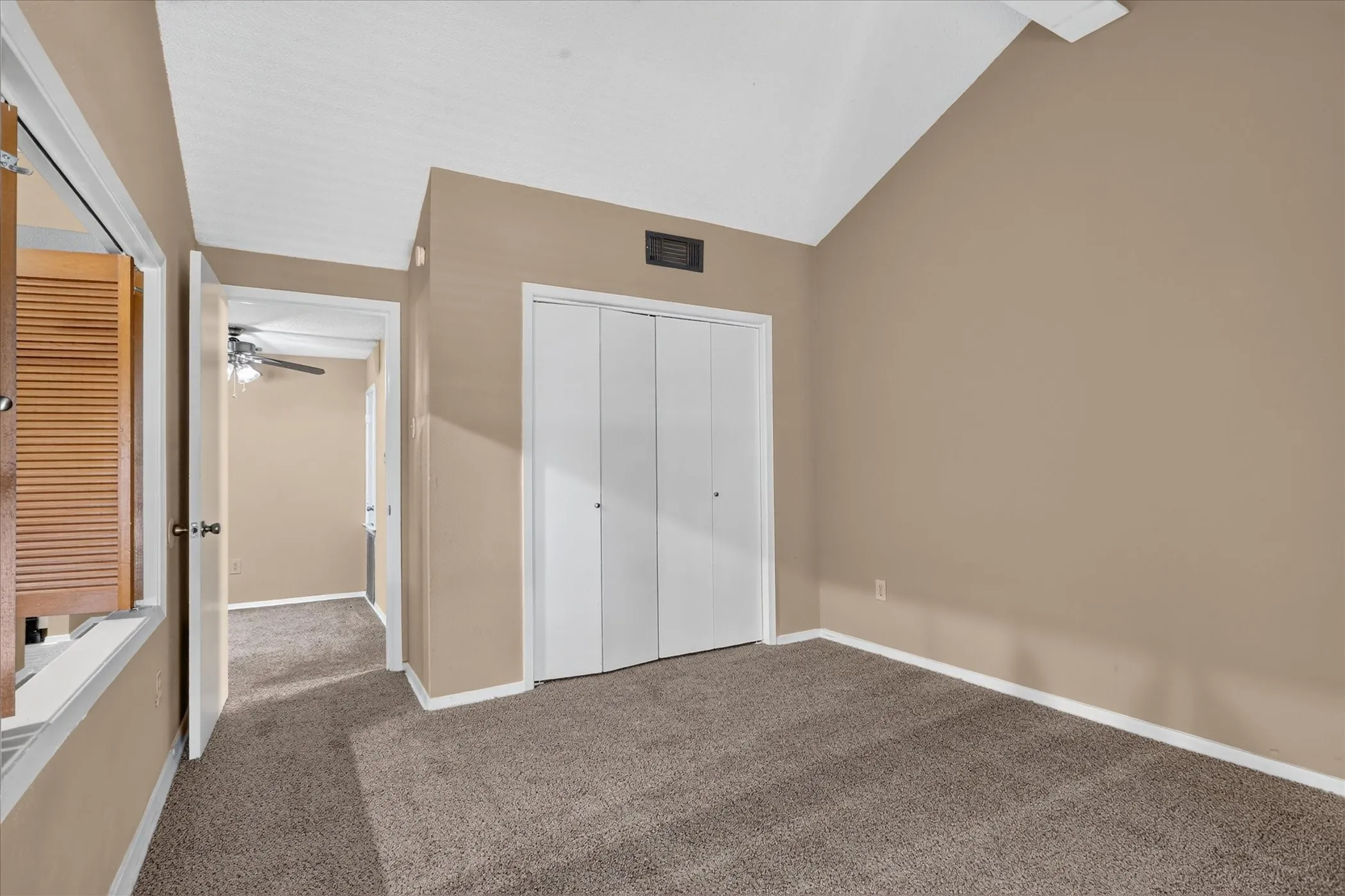 Vaulted ceiling, carpet flooring, bi-fold closet doors, louvered window shutters, recessed light fixture