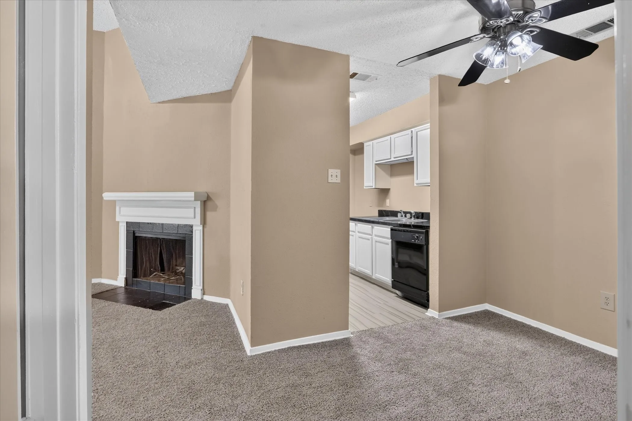 Carpeted living area with a ceiling fan, fireplace featuring a white mantel, and neutral wall tones