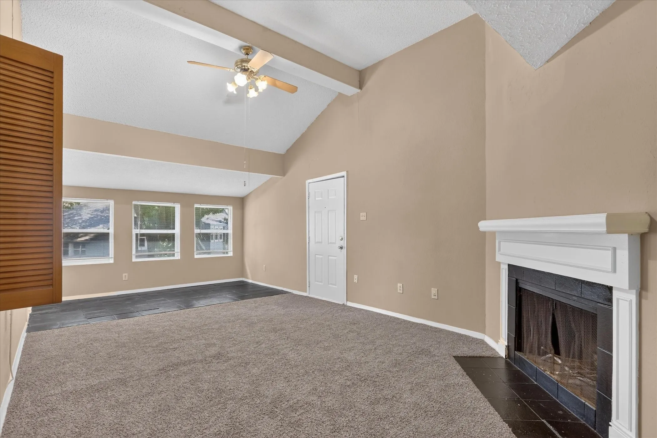 Vaulted ceiling with exposed beams, ceiling fan, and multiple windows